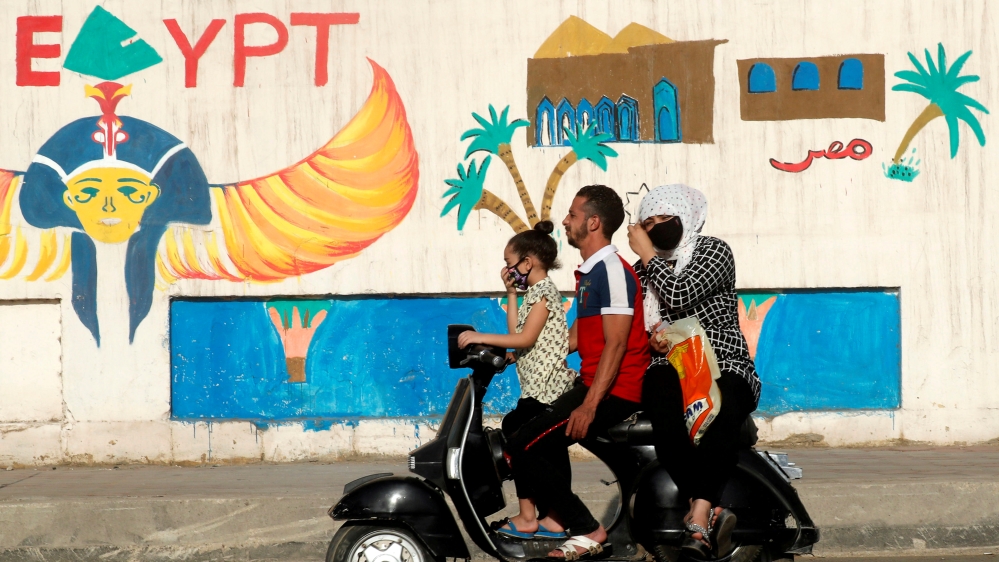 A man rides a motorcycle with his family in Cairo