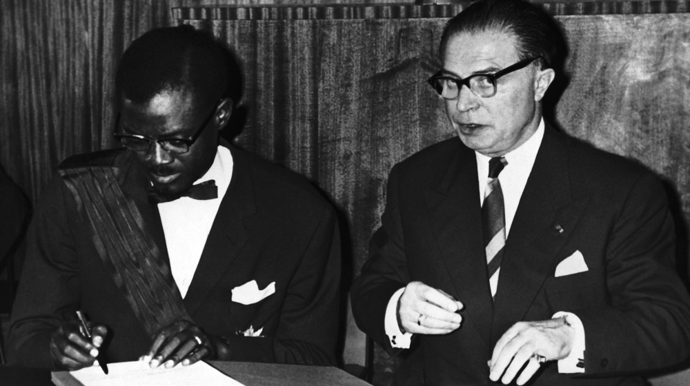 Patrice Lumumba, the Prime Minister of the Congo, signs the act of independence of the Congo in Leopoldville, Congo on June 30, 1960. At right is Gaston Eyskens, Prime Minister of Belgium, who signed
