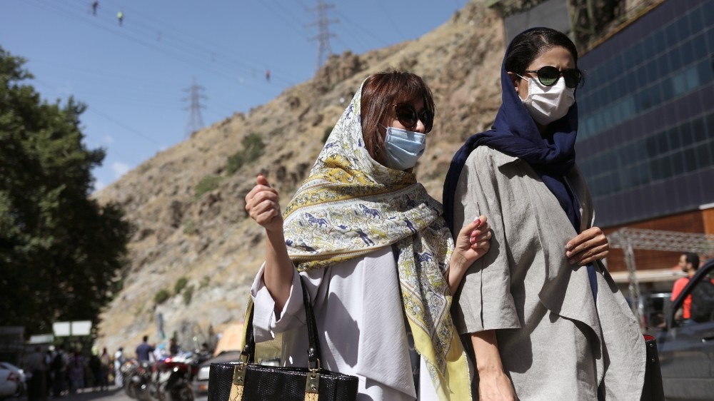 Iranian women wearing protective face masks walk in Darband street