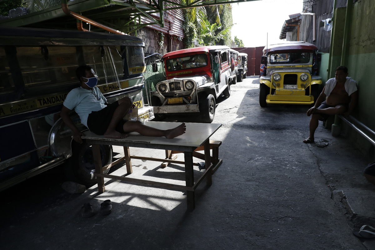 Driver Rey Escanilla, left, sits beside parked jeepneys at the Tandang Sora terminal which have been home for them since a lockdown started three months ago, on Wednesday, June 17, 2020 in Quezon city