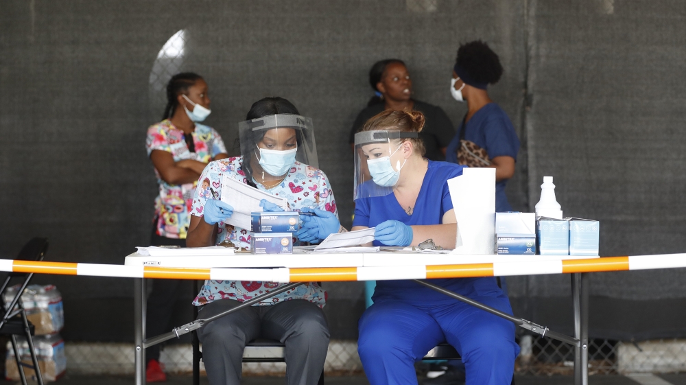 Healthcare workers Peggy Quartrman (L) and Tiffany Burke prepare to register patients during the COVID-19 drive-thru testing at the Duke Energy for the Arts Mahaffey Theater on July 8, 2020 in St. Pet