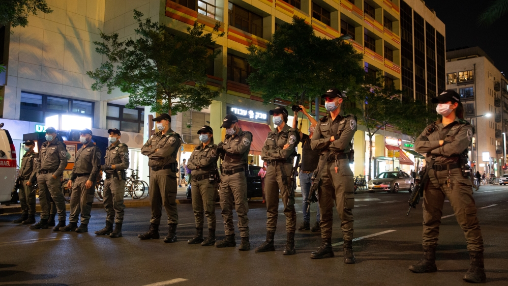 Israeli police officers in Tel Aviv stand guard as people gather to stage a demonstration in accordance with social distancing due to the coronavirus pandemic
