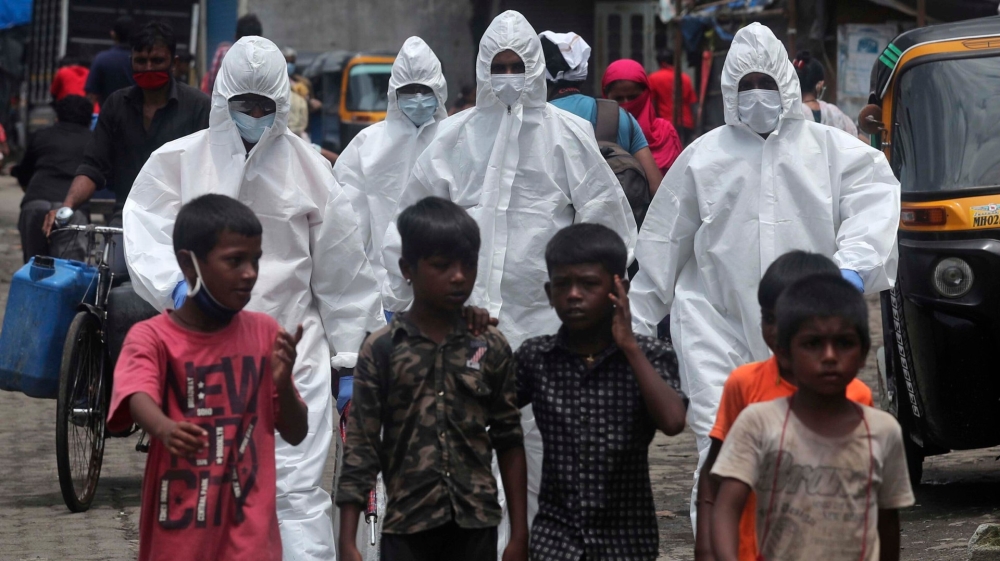 Health workers arrive to screen people for COVID-19 symptoms at a slum in Mumbai, India