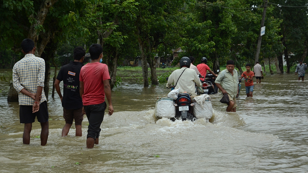 epa08513741 Villagers wade through the flood waters at Chamata in the Nalbari district of Assam, India, 28 June 2020. According to media reports, more than 200,000 people have been affected by the flo