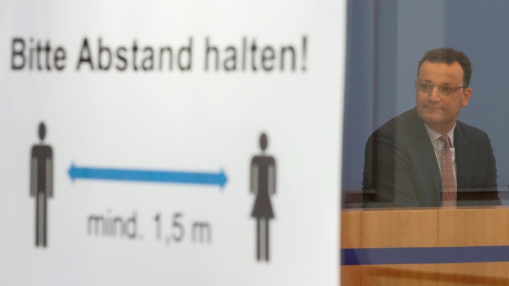 German Health Minister Jens Spahn is seen next to a social distancing sign reading ‘Please keep a distance’ during a news conference