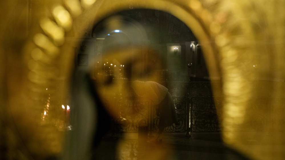 An Orthodox Christian reflected in an icon during a service inside a church in Moscow, Russia