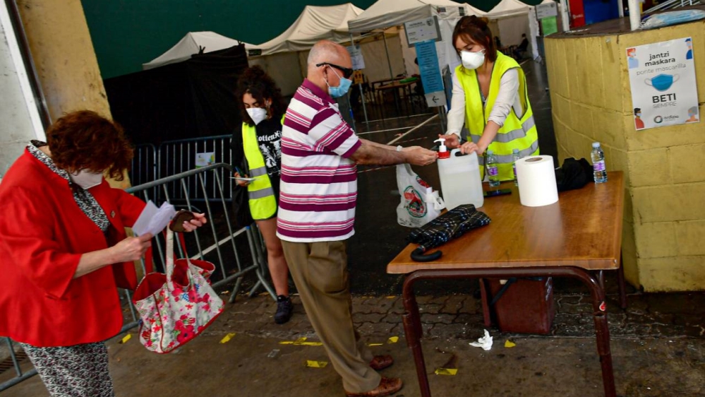 A resident cleans his hands before entering a polling station wearing a face mask to help curb the spread of the coronavirus, during the Basque regional election in the village of Ordizia, northern Spain on Sunday