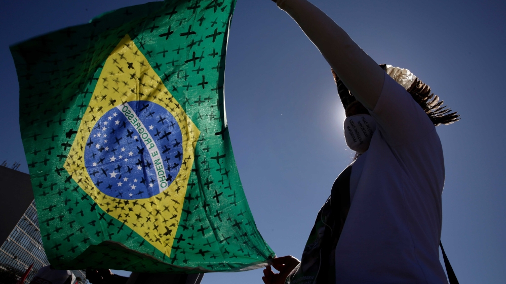 A demonstrator holding a Brazilian flag painted with crosses symbolizing the thousands of deaths due to the new coronavirus during a protest demanding President Jair Bolsonaro be impeached