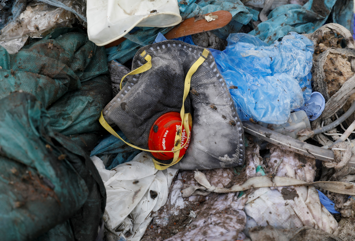 A discarded N95 protective face mask lies amongst other bits of disposed medical waste at a landfill site, during the coronavirus disease (COVID-19) outbreak, in New Delhi, India, July 22, 2020. REUTE