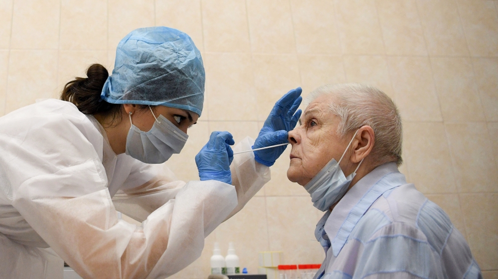 A medical worker wearing protective equipment takes a swab from a woman at a medical facility in Moscow on July 16, 2020, on the first day the Russian capital started providing free testing for the co