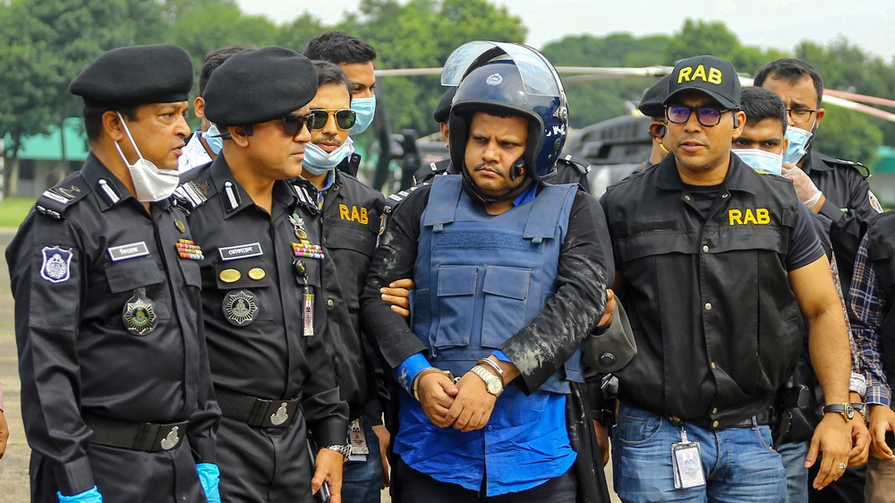 Hospital owner Mohammad Shahed accompanied by RAB officers after his arrest [AFP]