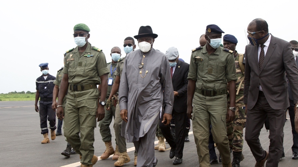 Former Nigerian President Goodluck Jonathan (2L) walks at the International Airport in Bamako upon his arrival on August 22, 202