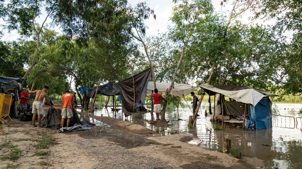 Matamoros, Mexico - asylum seekers work to remove rubbish from the banks of the swelling river and to salvage what materials they can.