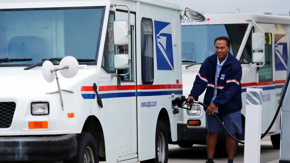 A US postal employee pumping gas into his mail delivery truck in San Diego, California