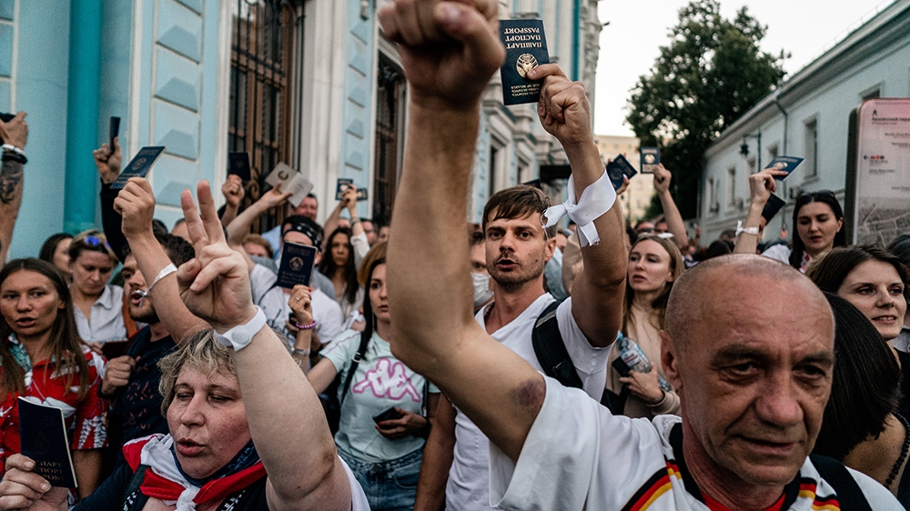 People hold up Belarusian passports as they protest outside the Belarusian embassy after polls closed in Belarus' presidential election, in Moscow on August 9, 2020. - Belarusian President Alexander L