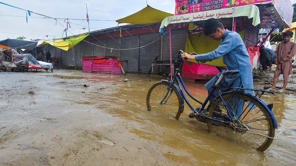 A flash flood affected villager pushes a bicycle along a road in Charikar, Parwan province, on August 26, 2020. - At least 46 people have been killed and hundreds of houses destroyed by flash floods a