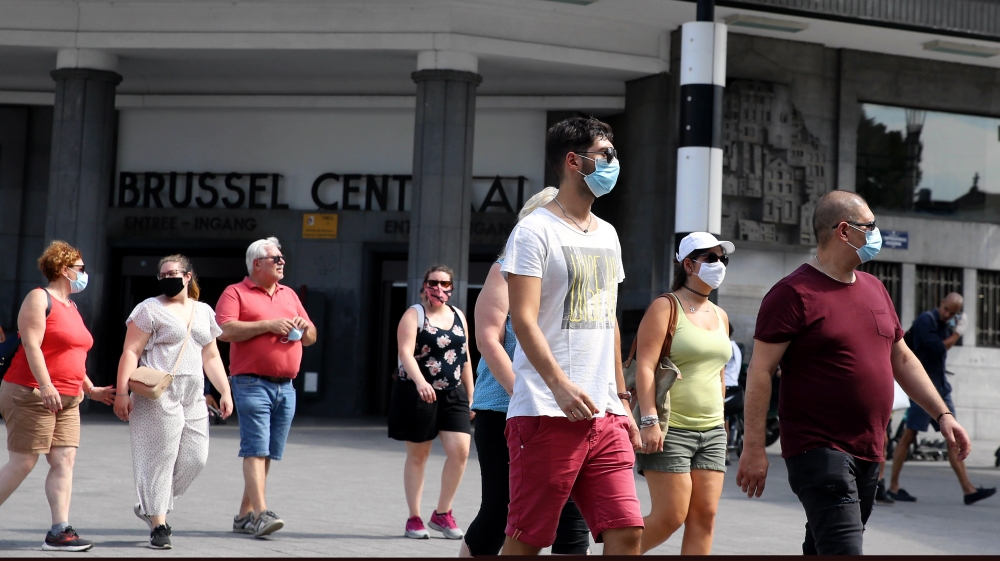 People wearing masks walk along a street as the tally for novel coronavirus cases passes 73,000 in Belgium