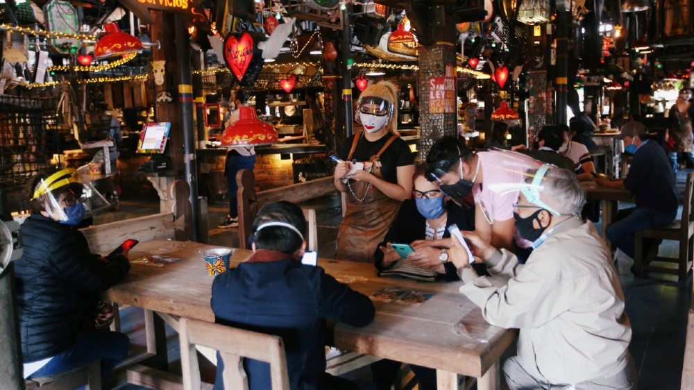 Customers wearing protective masks talk to a waiter at the Andres Carne de Res restaurant, amidst the coronavirus disease (COVID-19) outbreak, in Chia, Colombia August 30, 2020. Picture 