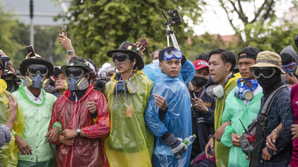 Pro-democracy protesters wearing masks sometimes used to avoid tear gas create a human chain during a march near Sanam Luang in Bangkok, Thailand, Sunday, Sept. 20, 2020. The mass student-led rally th