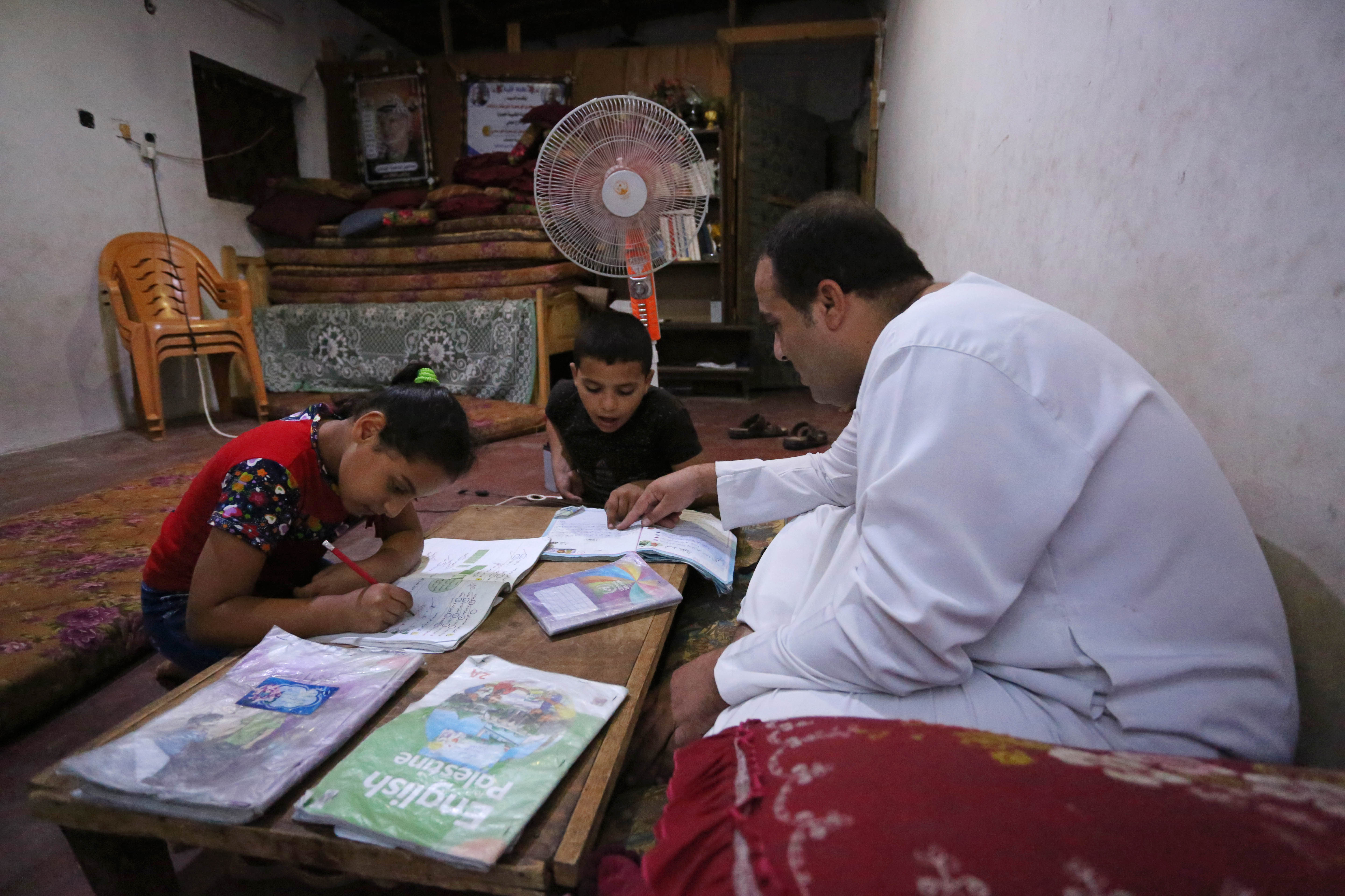 Ismael Sulaiman, 38, teaches his children after following up with their teacher remotely through WhatsApp amid coronavirus school closures [Ashraf Abu Amra/Al Jazeera]