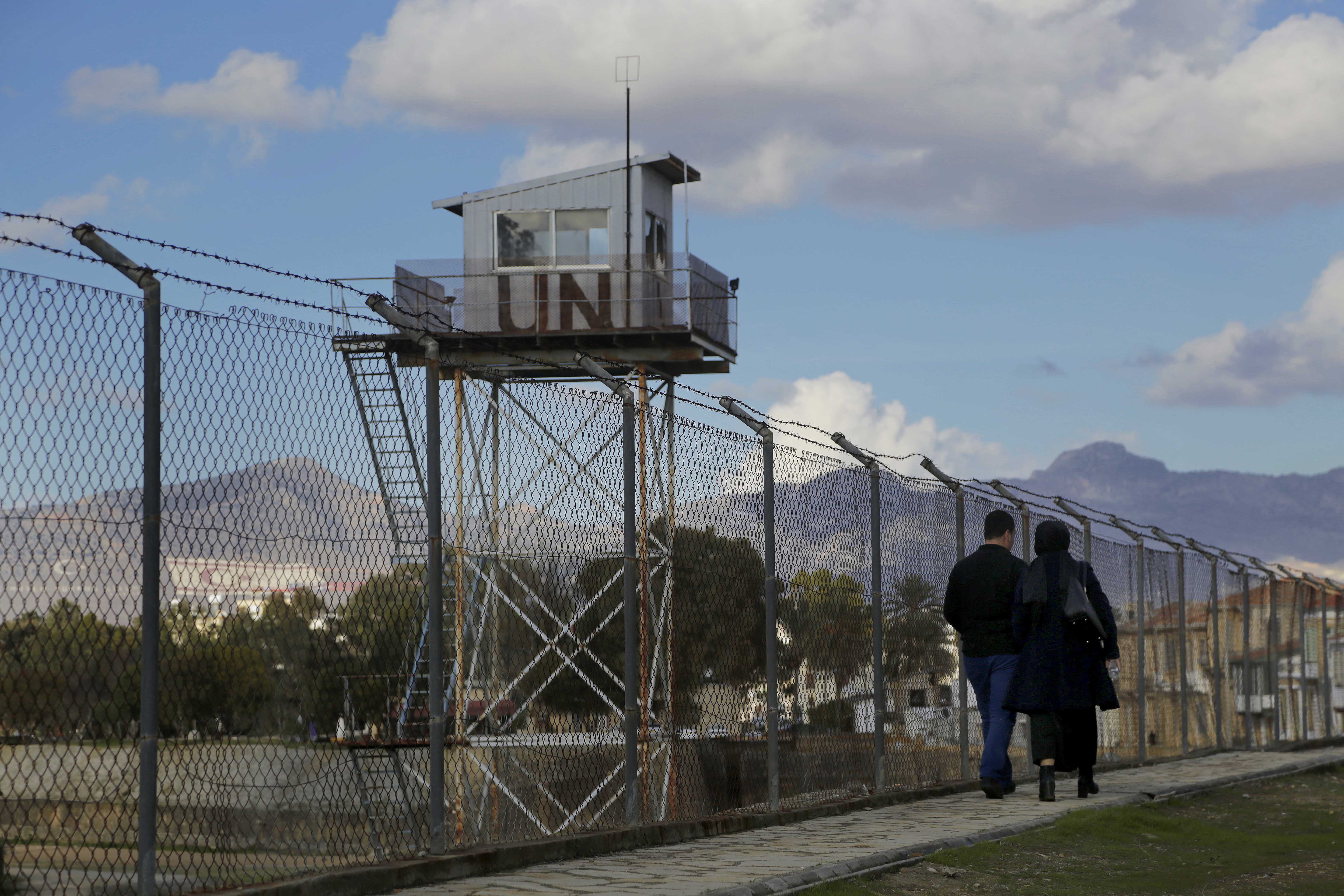 A couple walk past a UN guard post at the fence that divides the Greek and Turkish Cypriots area in Cyprus