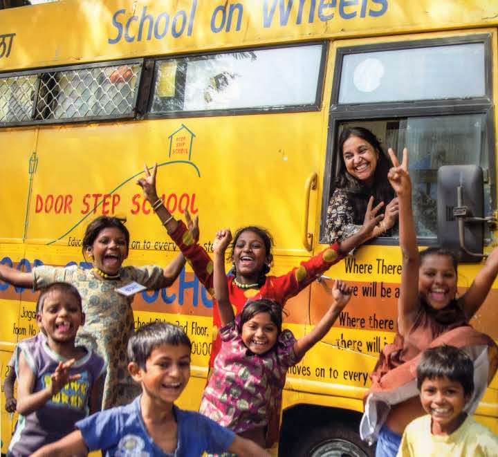 Bina and students pose by a school-on-wheels bus [Photo courtesy of the Door Step School]
