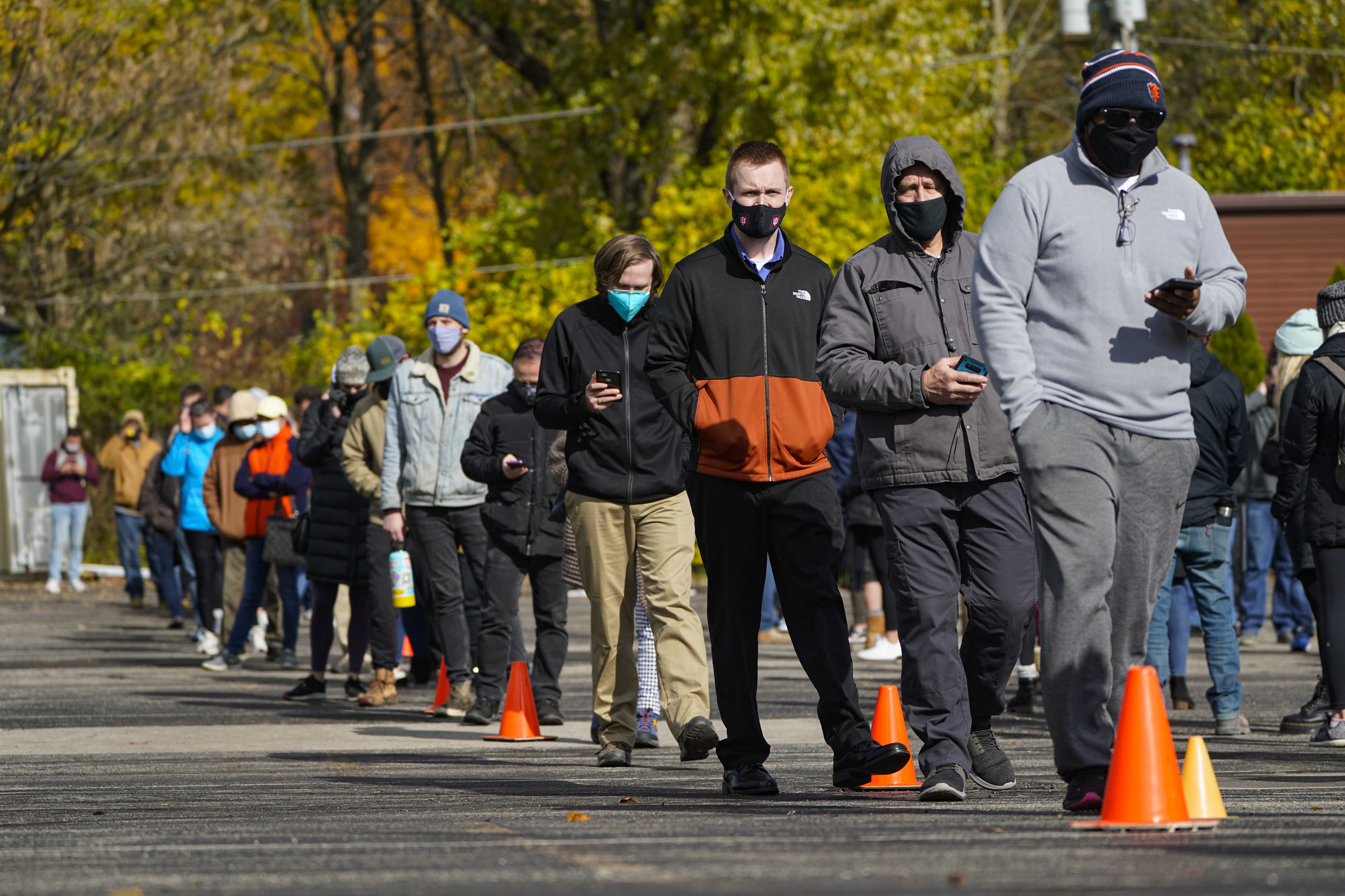 Voters wait in long lines to cast their ballots during early voting at St. Luke's United Methodist Church in in Indianapolis, Friday, Oct. 30, 2020. The wait to vote at this location is expected to be over 5 hours. (AP Photo/Michael Conroy)