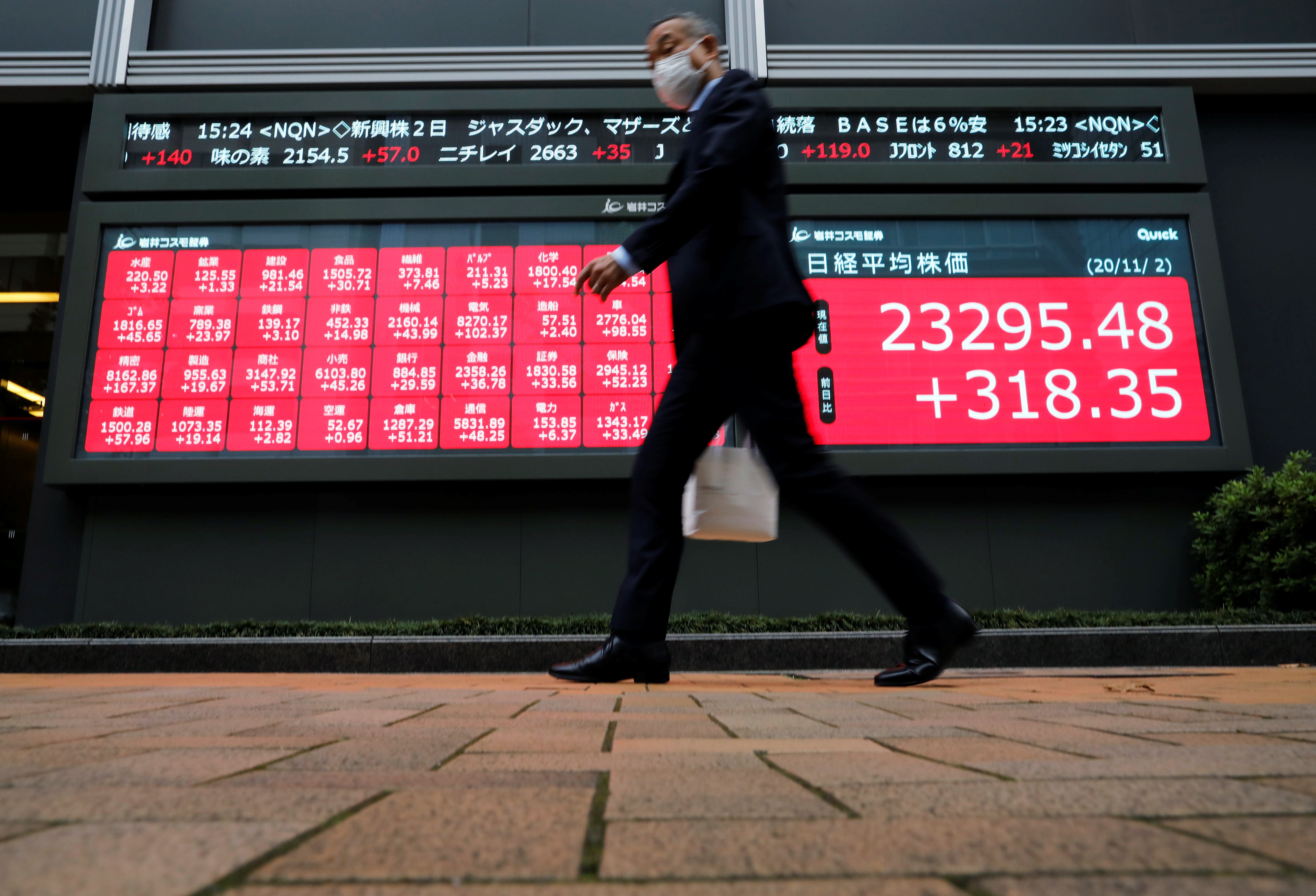 A man walks past stock figures in Tokyo, Japan.