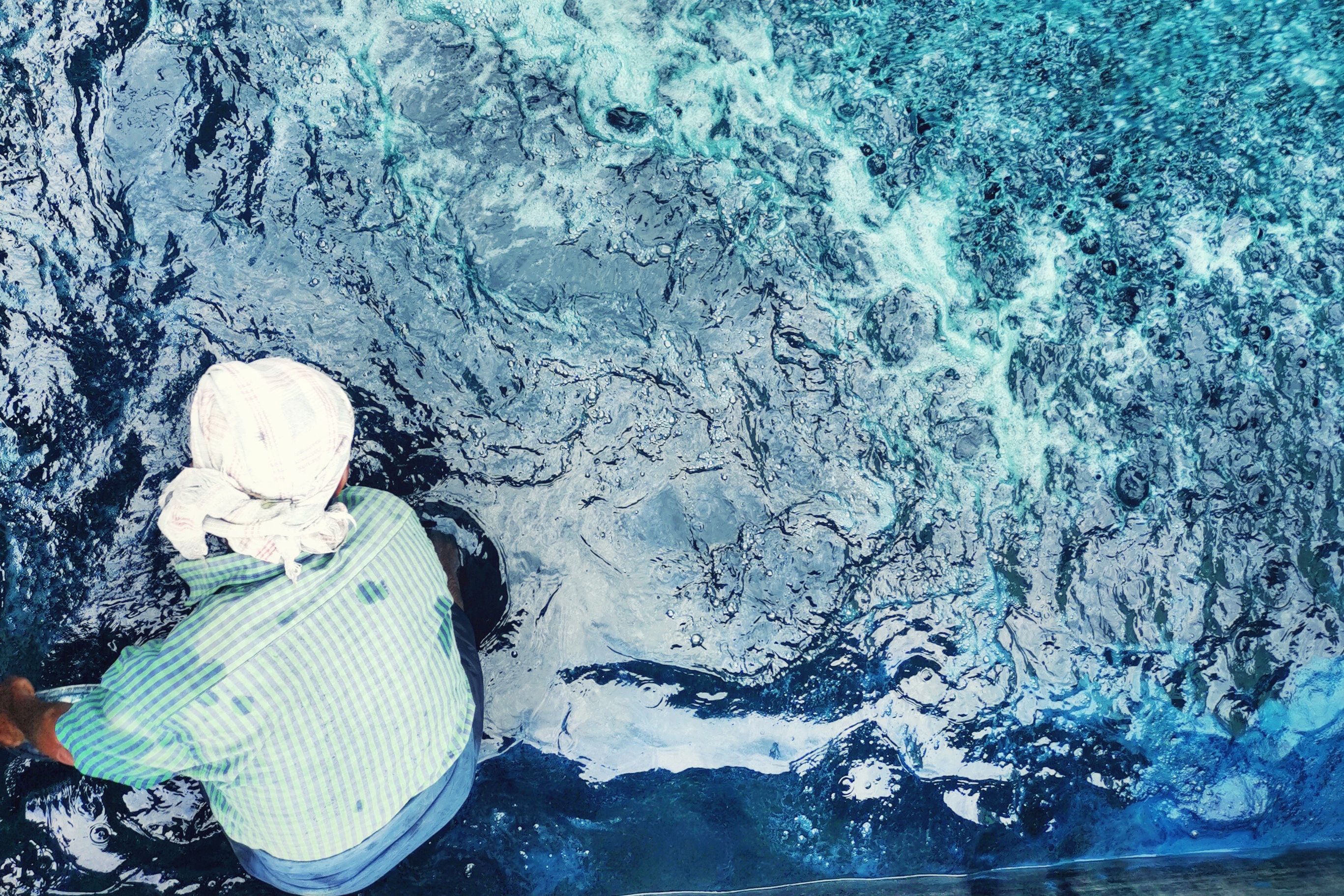 A labourer works in an indigo processing tank where water is oxidised until it turns from greenish to blue [Bala Natrajan/Al Jazeera]