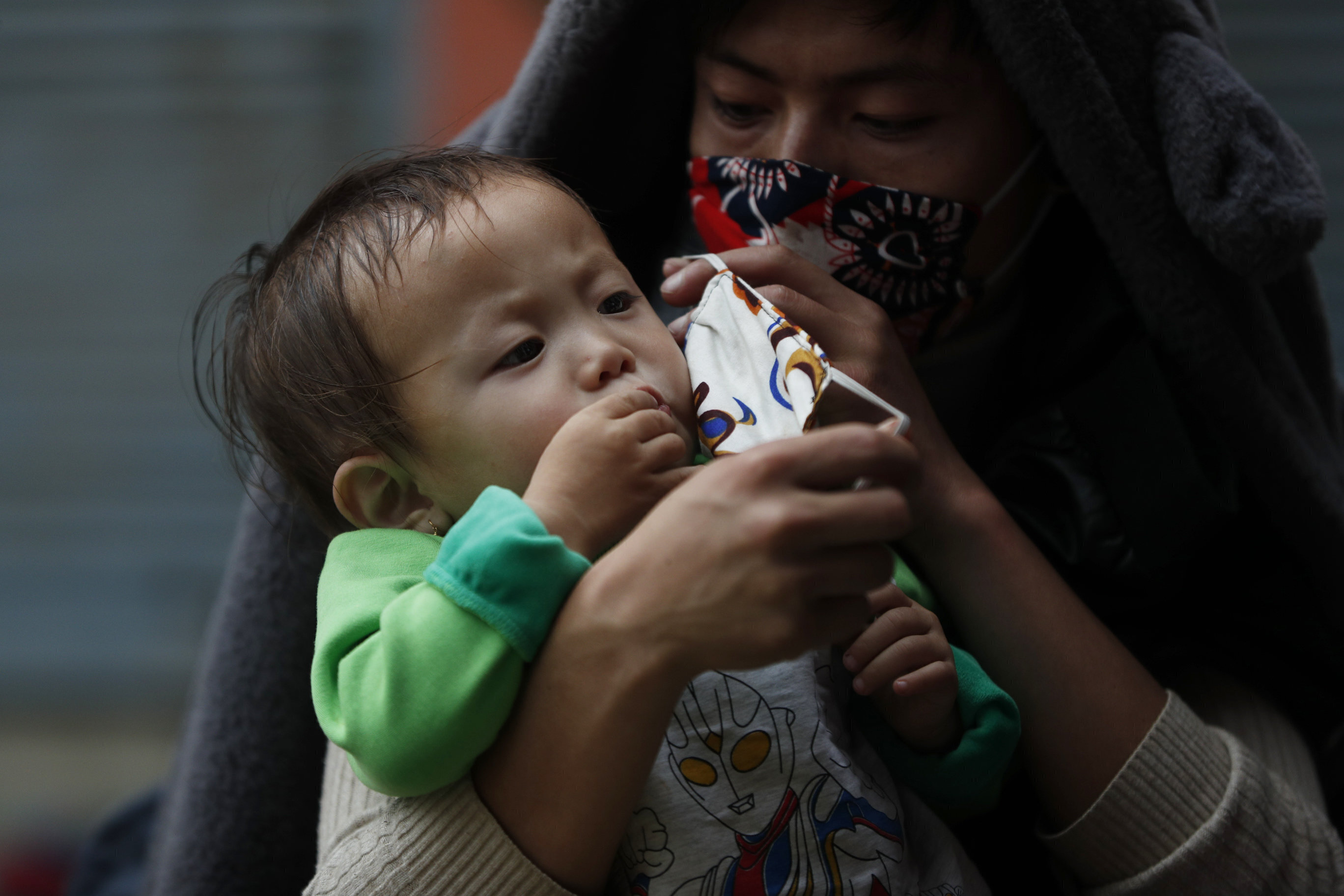 A Nepalese man puts a mask on his child's face [File: Niranjan Shrestha/AP]