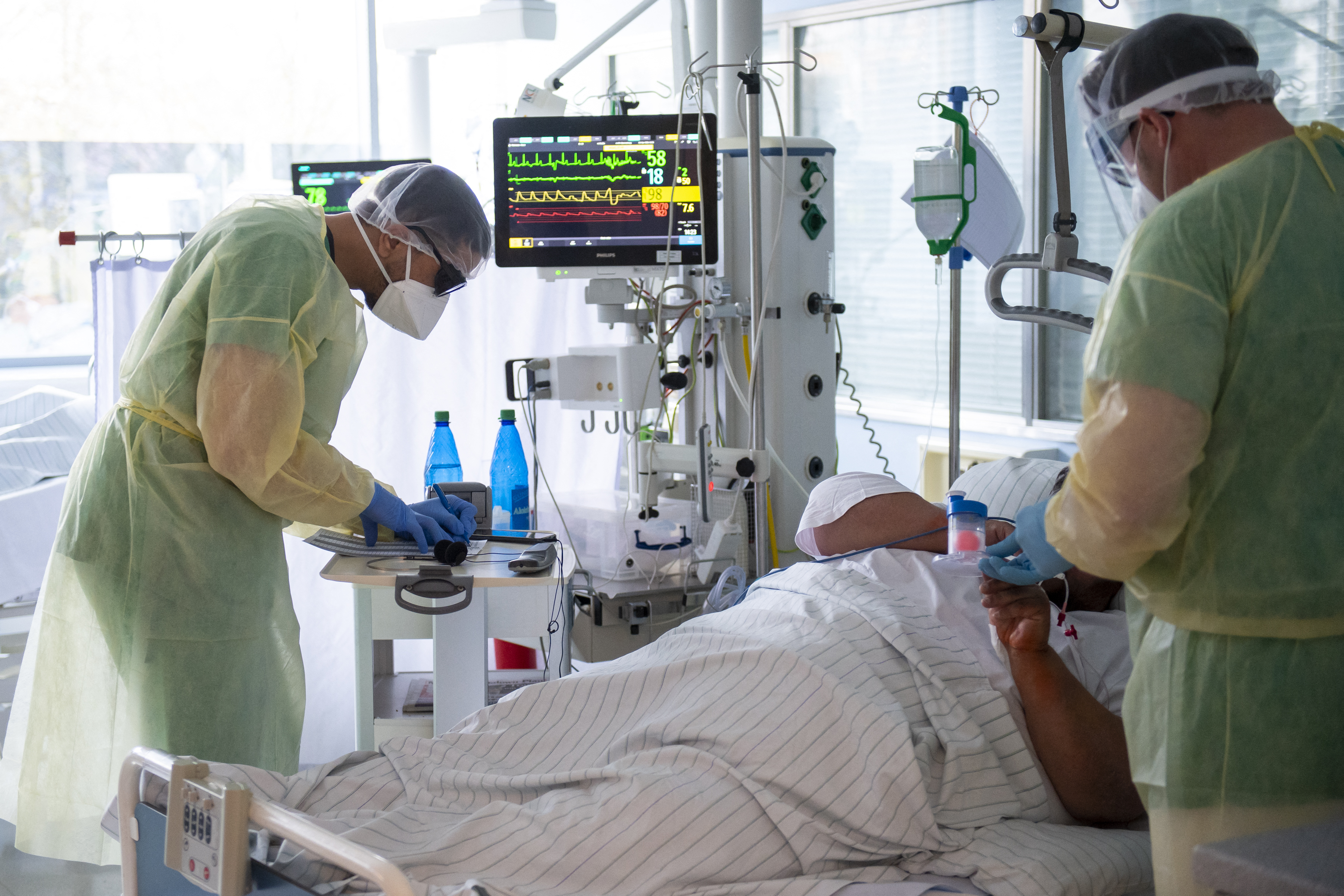Senior doctor Thomas Marx (R) talks to a patient infected with the novel coronavirus (Covid-19) in an intensive care unit (ICU) at the hospital in Freising, southern Germany [Lennart Preiss/AFP]