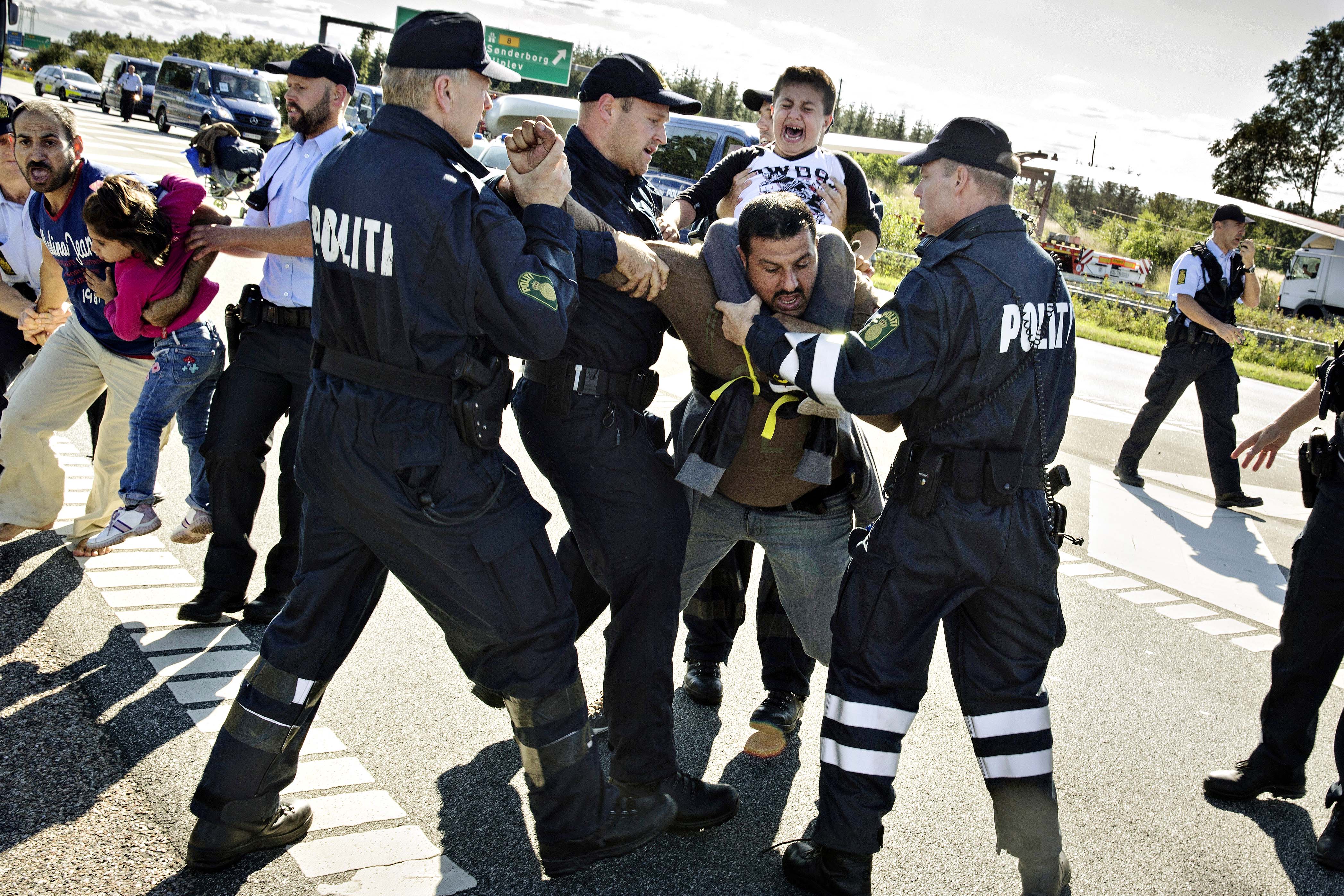 In this image from September 9, 2015, police grab a refugee as hundreds walk on a motorway near Padborg in Denmark [File: Martin Lehmann/AP Photo/POLFOTO]