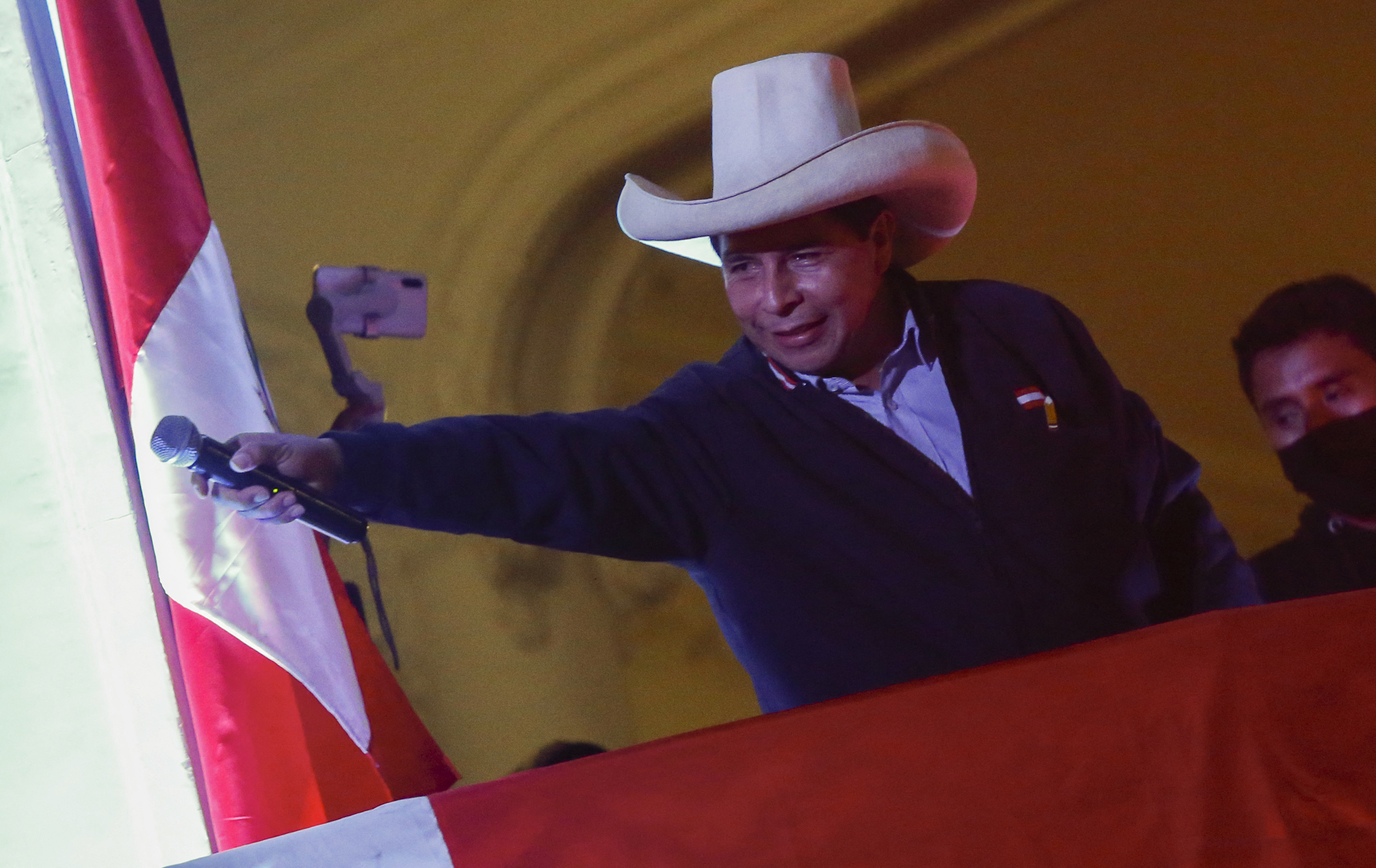Peru's left-wing presidential candidate Pedro Castillo gestures to his supporters from the balcony of his party headquarters in Lima on June 10 [Gian Masko/AFP]