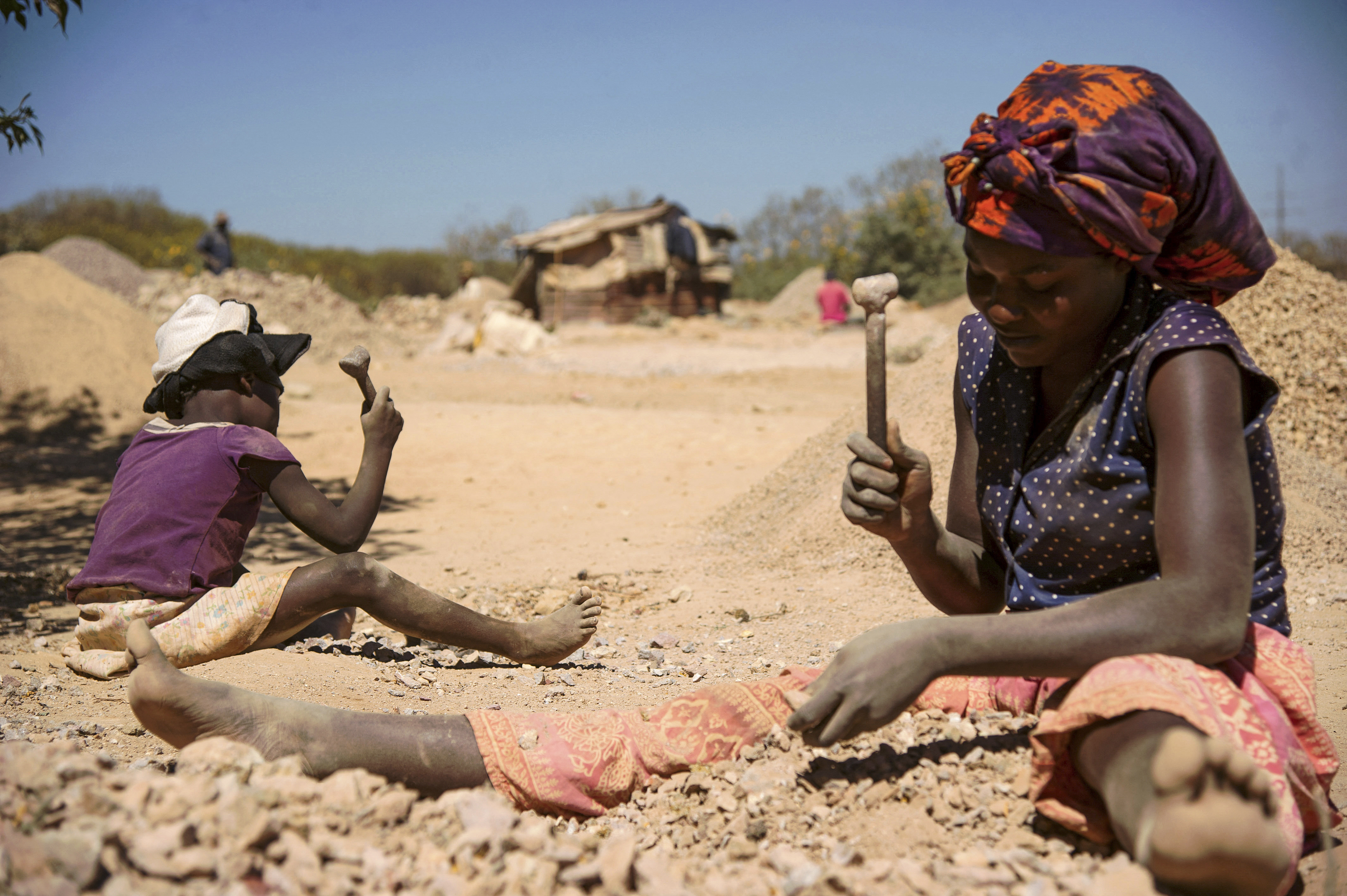 A child and a woman break rocks extracted from a cobalt mine at a copper quarry and cobalt pit in Lubumbashi, DRC [File: AFP/Junior Kannah]