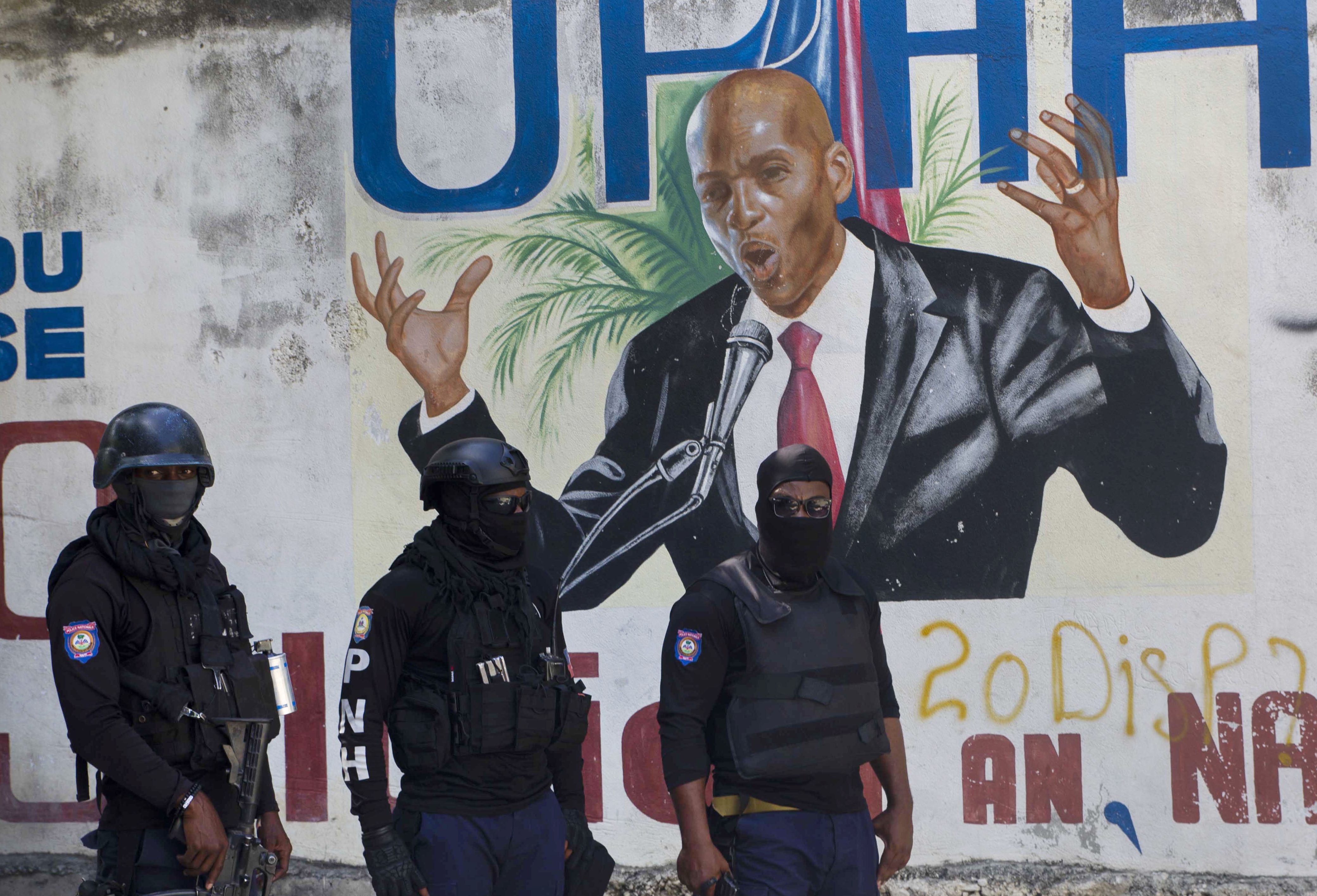 Police stand in front of a mural depicting slain Haitian President Jovenel Moise