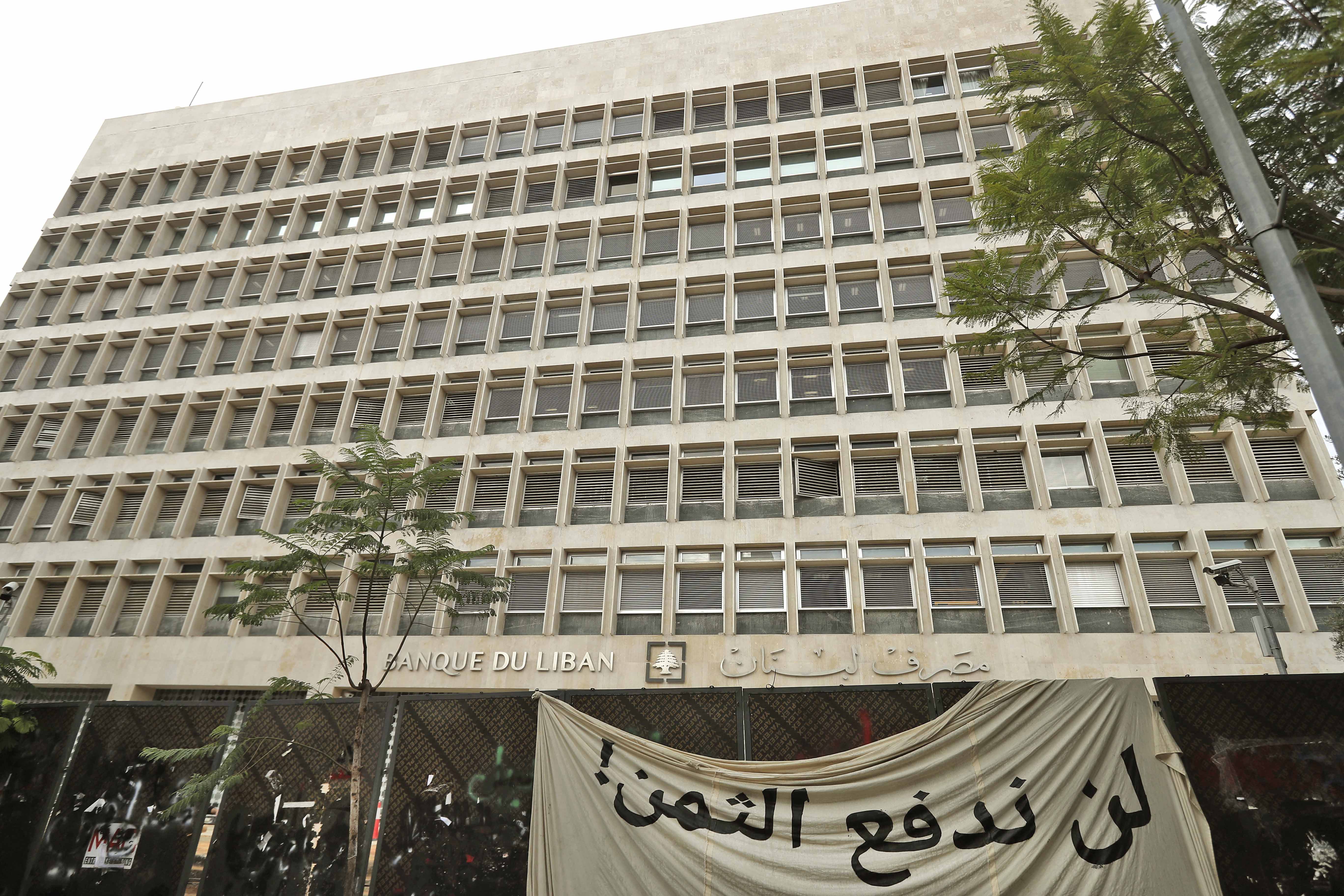 This picture taken on November 27, 2019 shows a banner in Arabic, reading "we will not pay the price", hanging outside the headquarters of the Banque du Liban in Beirut [File: AFP/Joseph Eid]