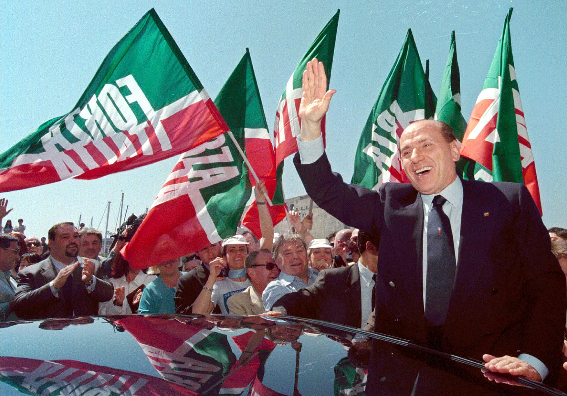 Silvio Berlusconi greets his supporters in Naples, Wednesday, May 2, 2001. In the background flags of Berlusconi's "Forza Italia" political party are waved
