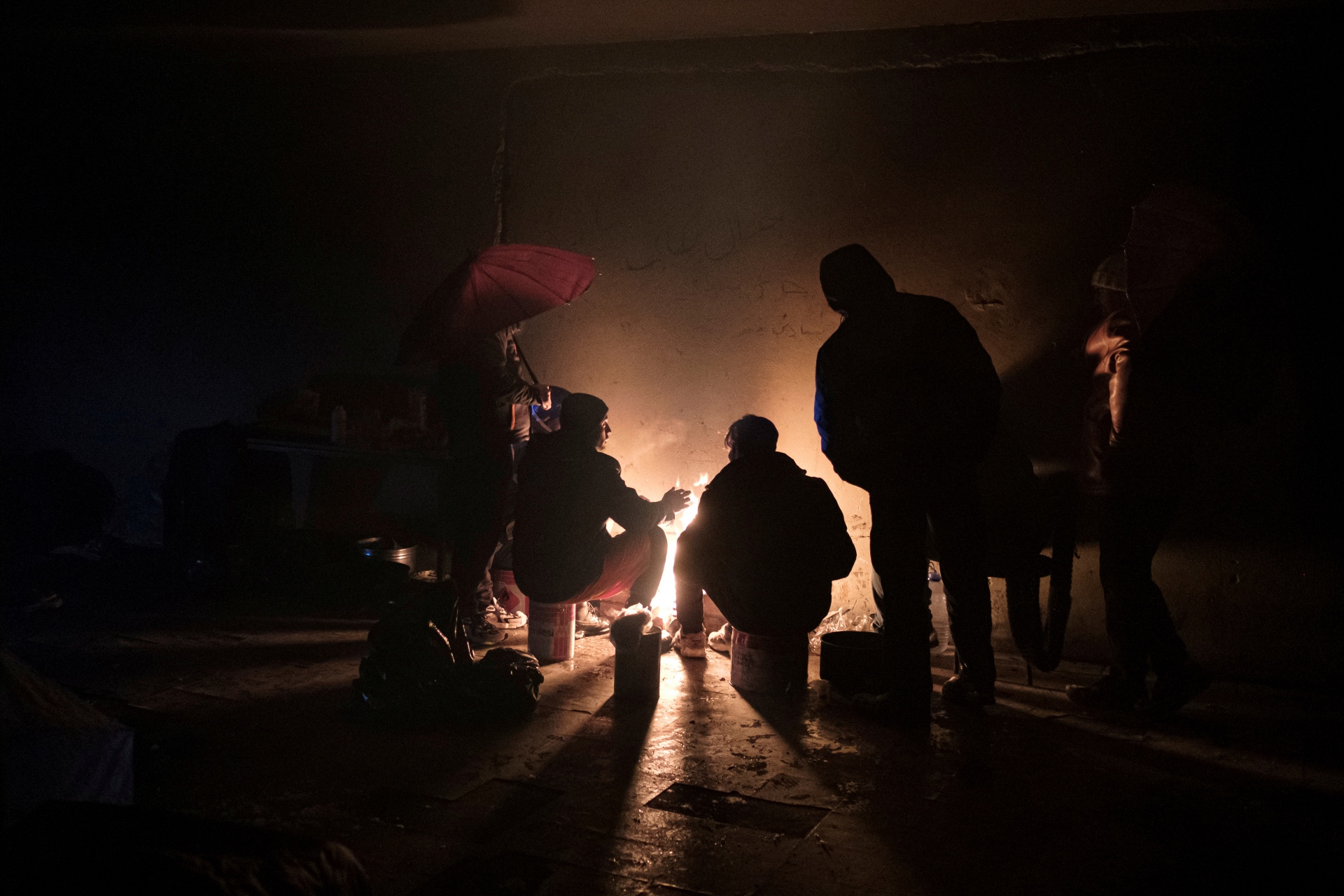 Asylum seekers warm themselves at an abandoned factory in the town of Bihac in Bosnia and Herzegovina, on January 10, 2021 [File: Reuters/Marko Djurica]