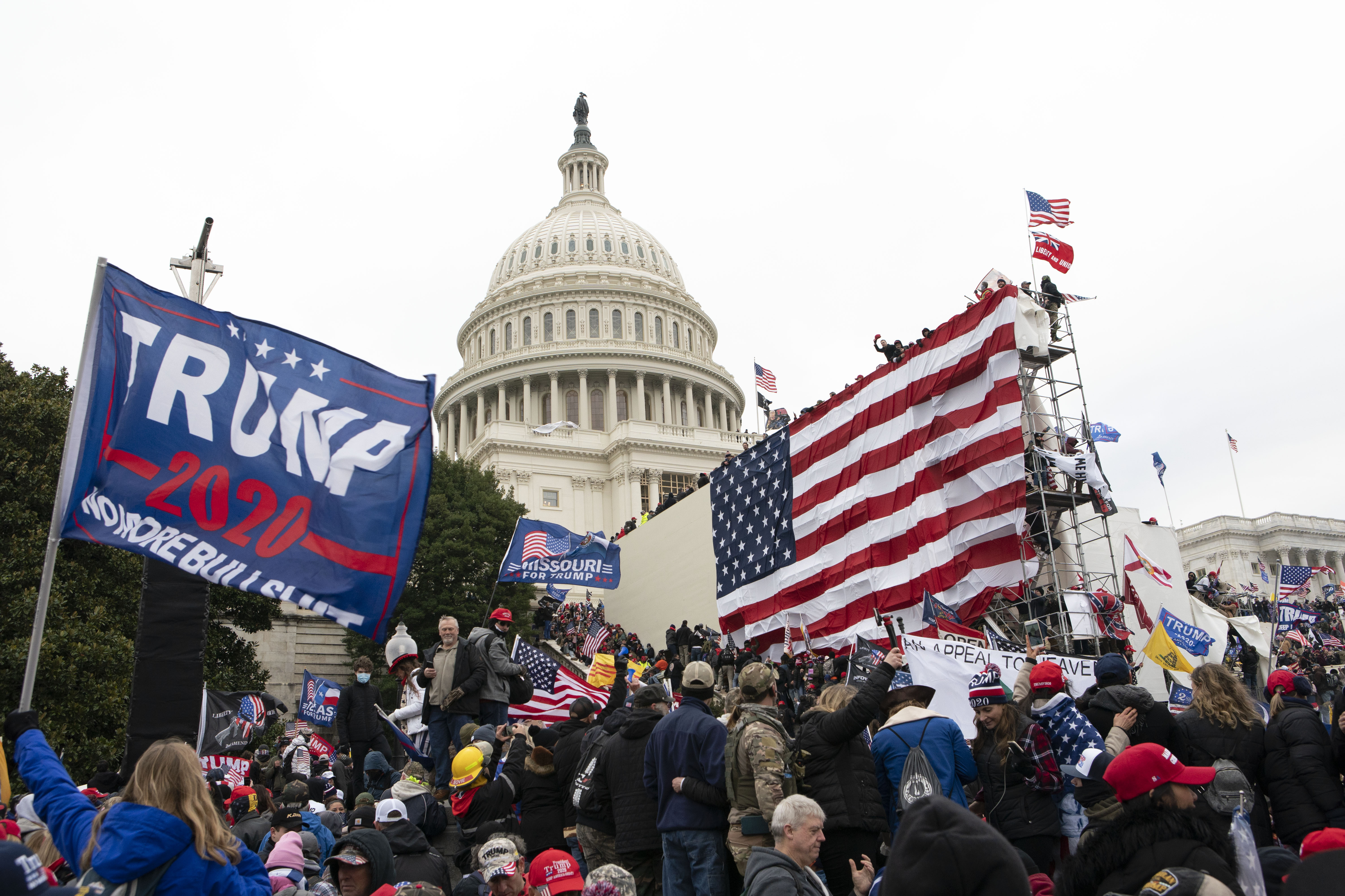 Crowd in front of US Capitol and a US flag and Trump flag