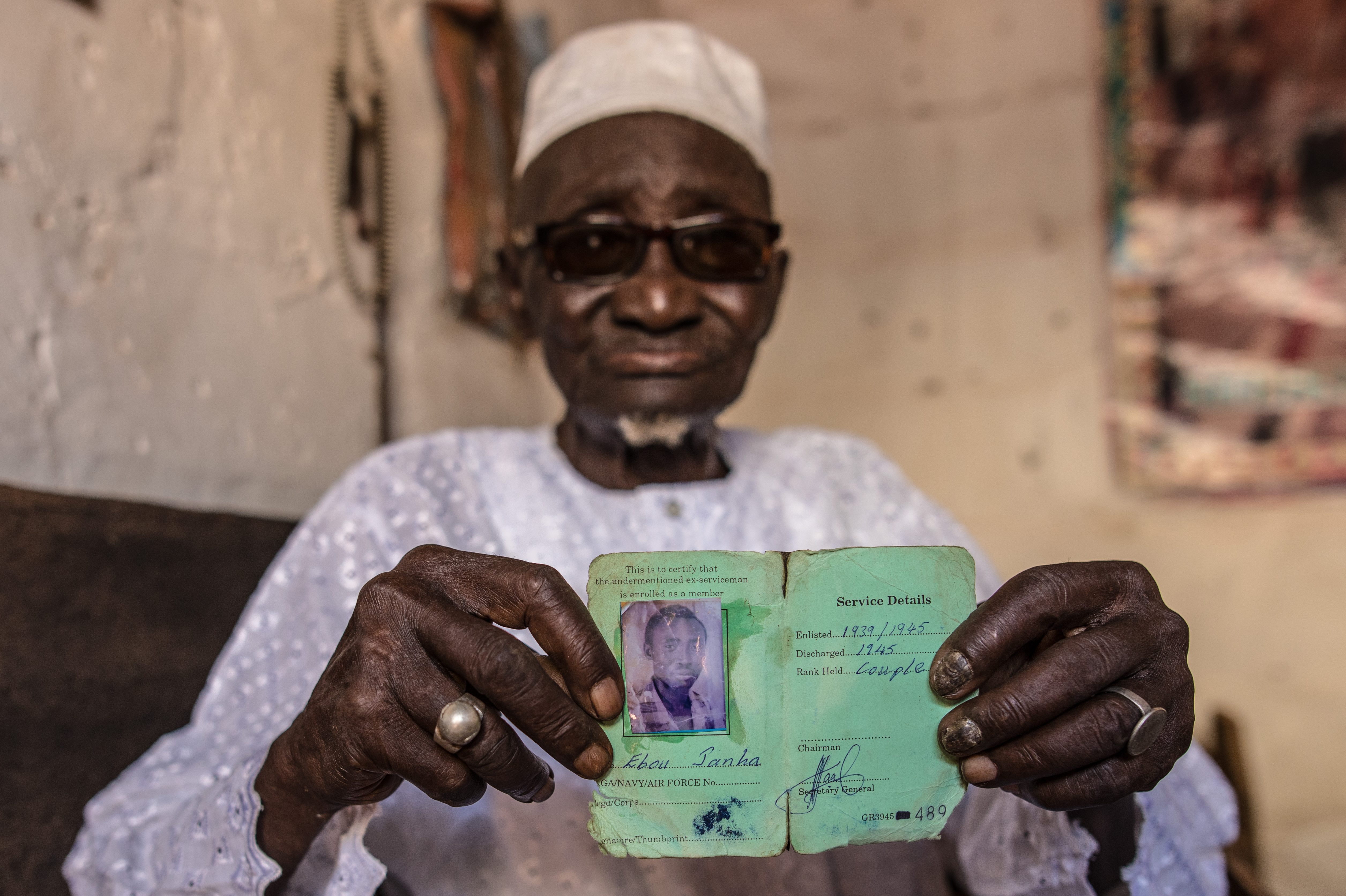 Ebou Janha holds a document showing his record of service during World War II [Muhamadou Mughtarr Bittaye/Al Jazeera]