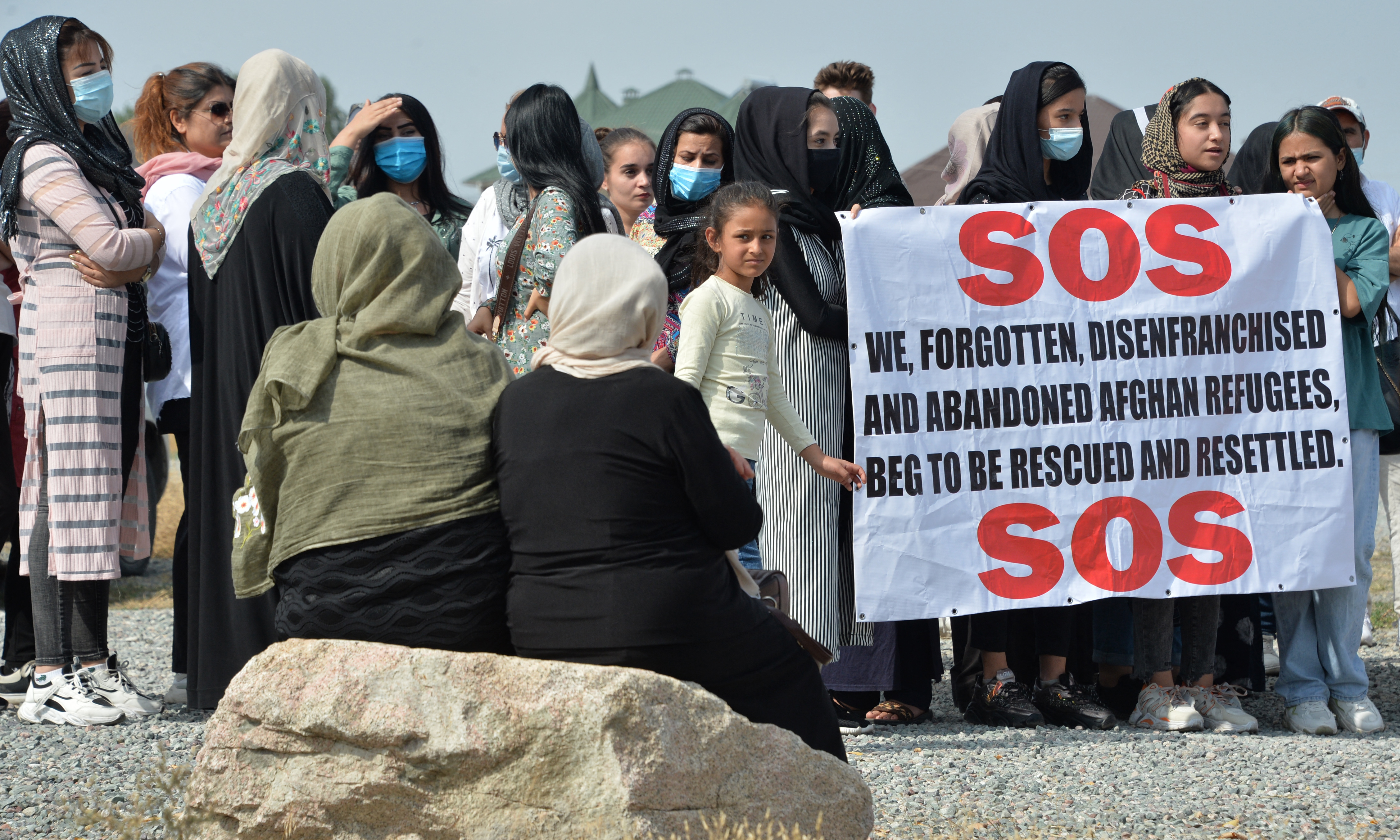 Afghan refugees, who fled Afghanistan in 1996, hold a poster as they attend a rally in front of the US Embassy in Bishkek, on August 19, 2021 [Vyacheslav Oseledko/AFP]