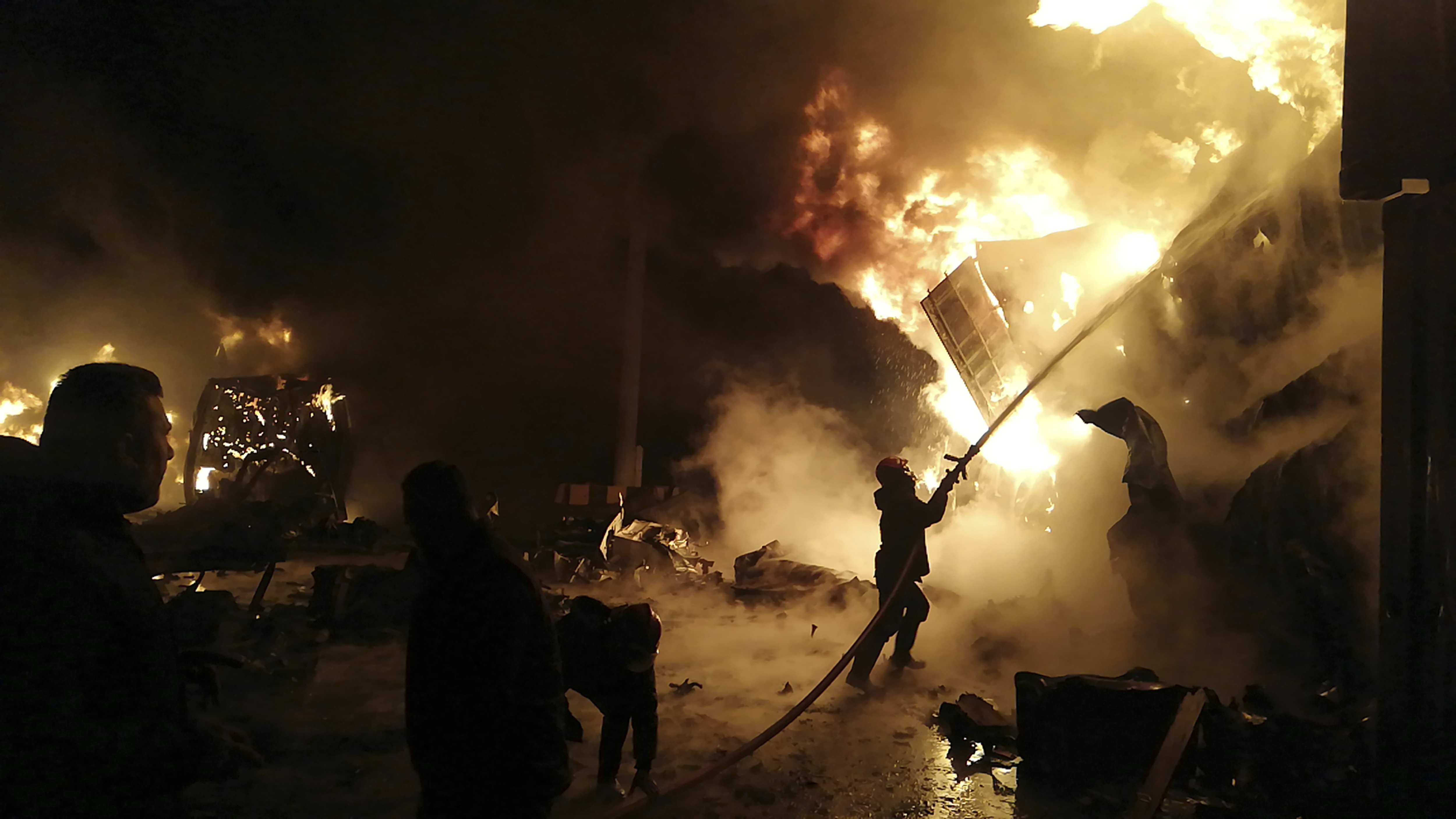 Firefighters work to extinguish flames on the site of a shipping container in the seaport of the Syrian city of Latakia.