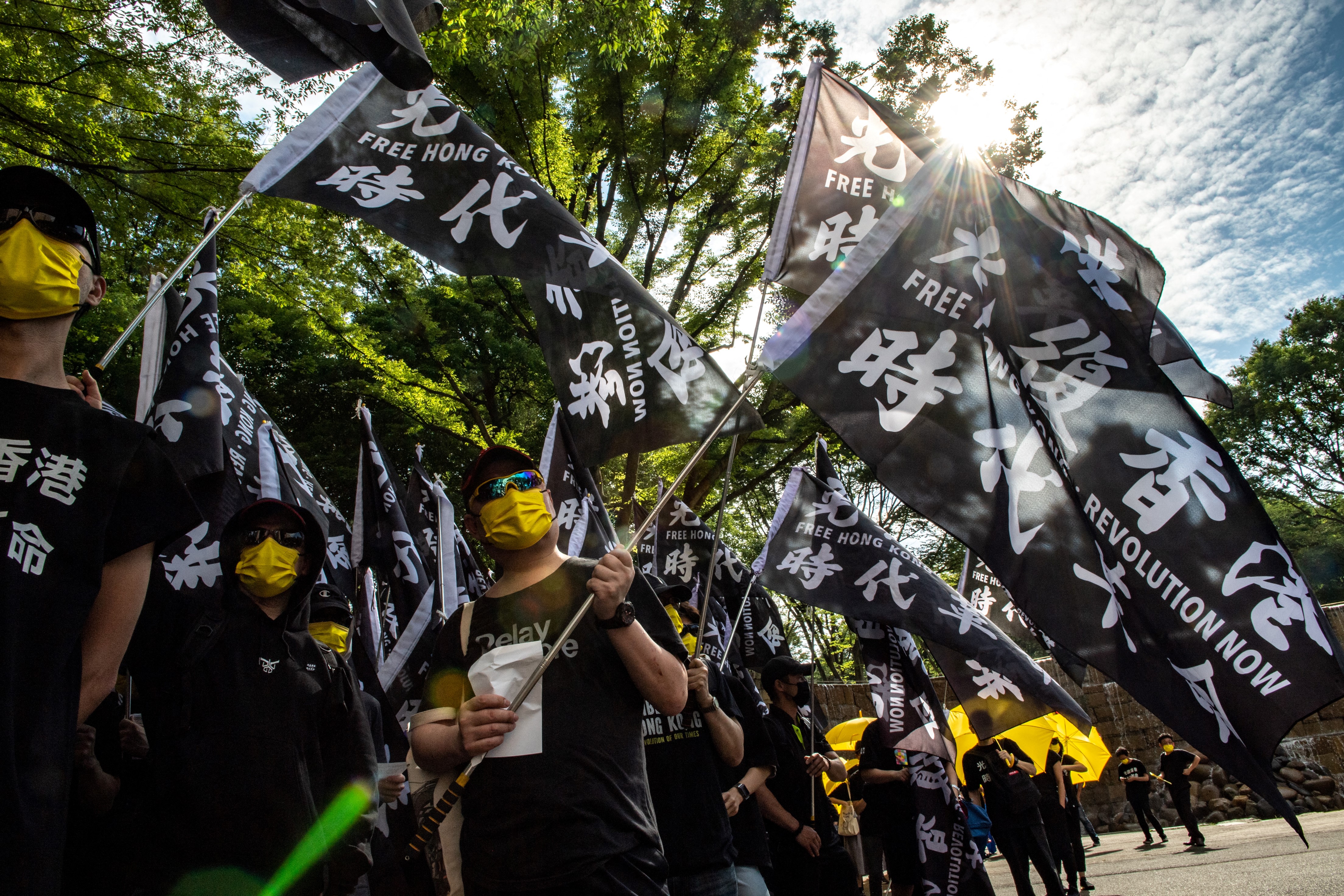 A group of black-clad protesters carrying flags reading liberate Hong Kong, revolution of our times", a slogan coined by activist Edward Leung