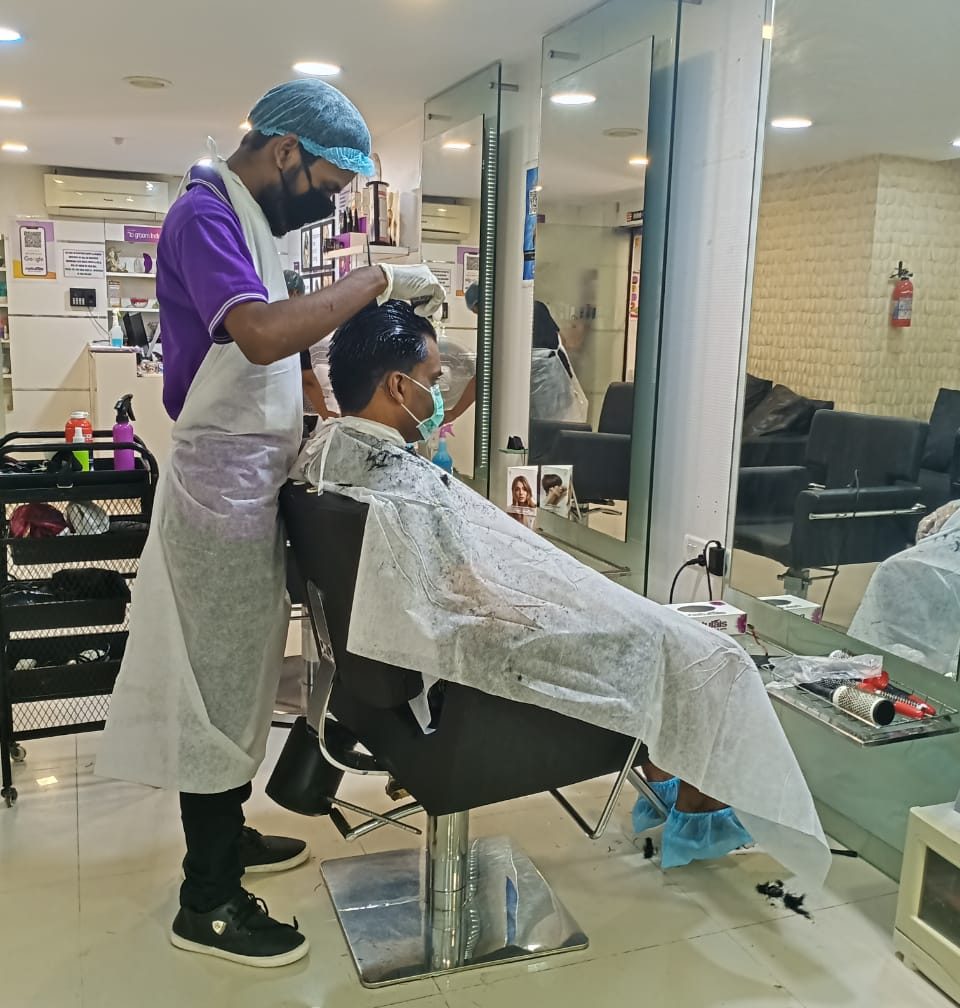 A barber cutting a male client's hair at a salon in India