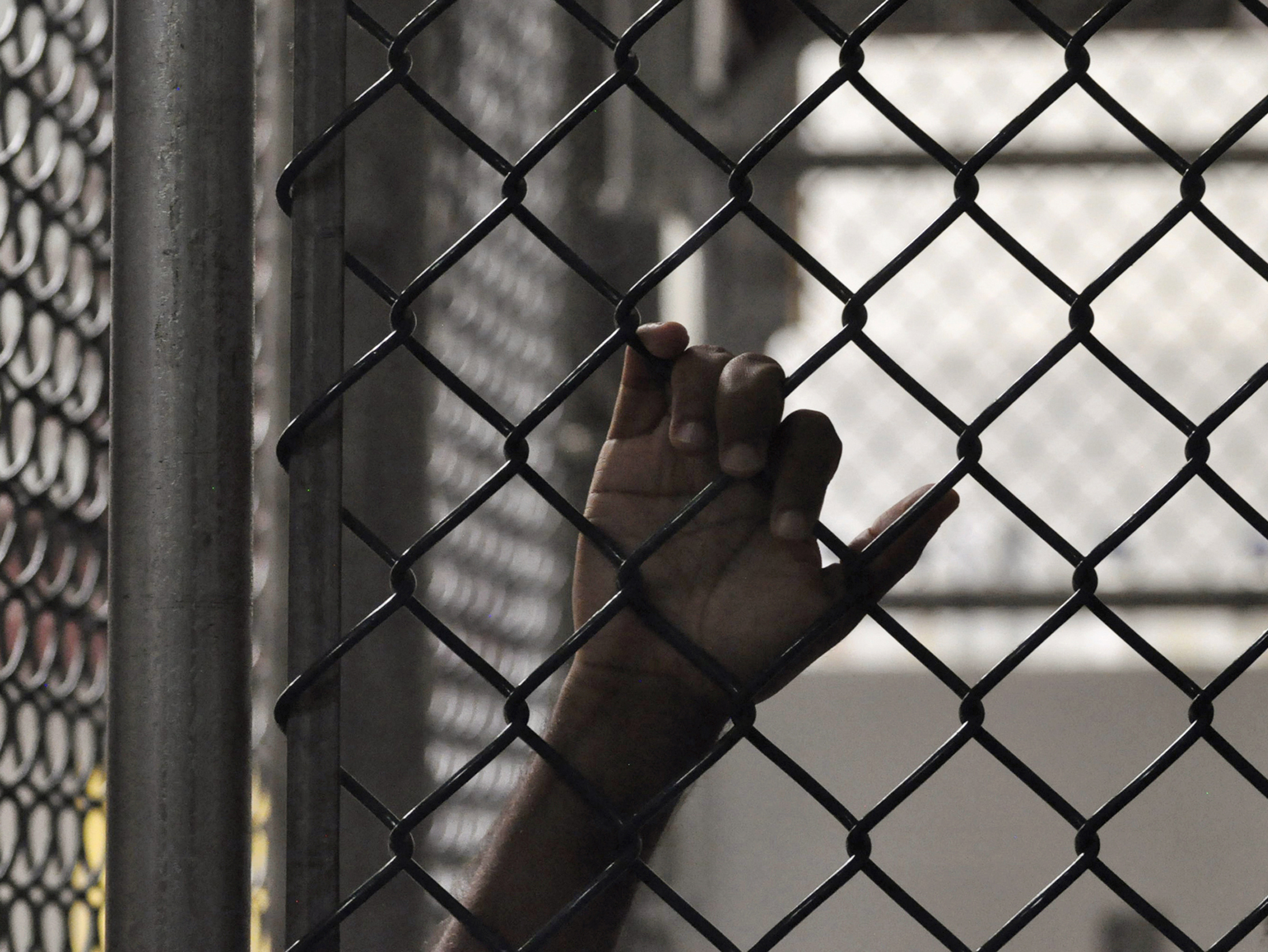A Guantanamo detainee holds onto a fence inside the Camp 6 high-security detention facility