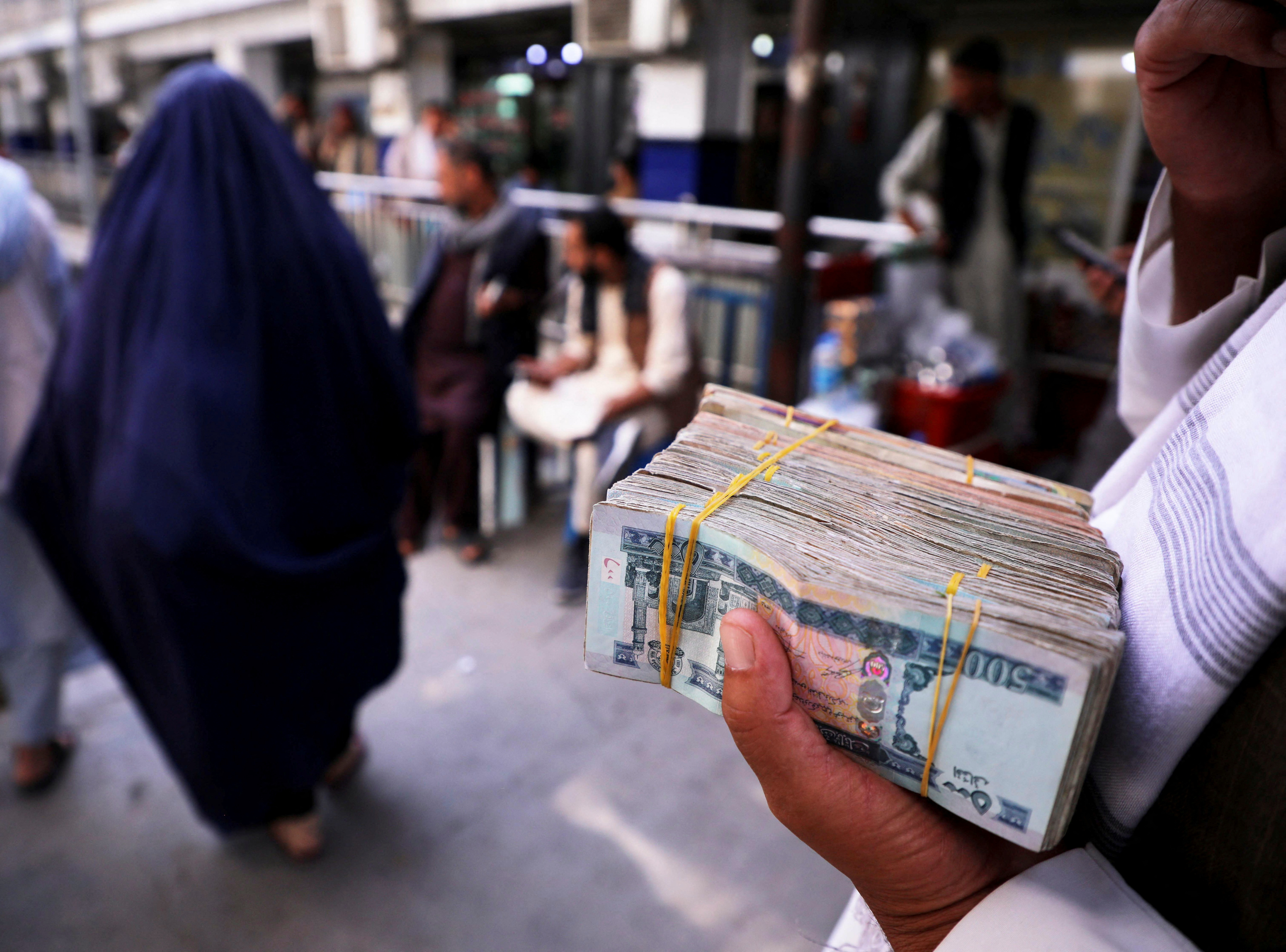 A person holds a bundle of Afghan afghani banknotes at a money exchange market, following banks and markets reopening after the Taliban took over in Kabul, Afghanistan