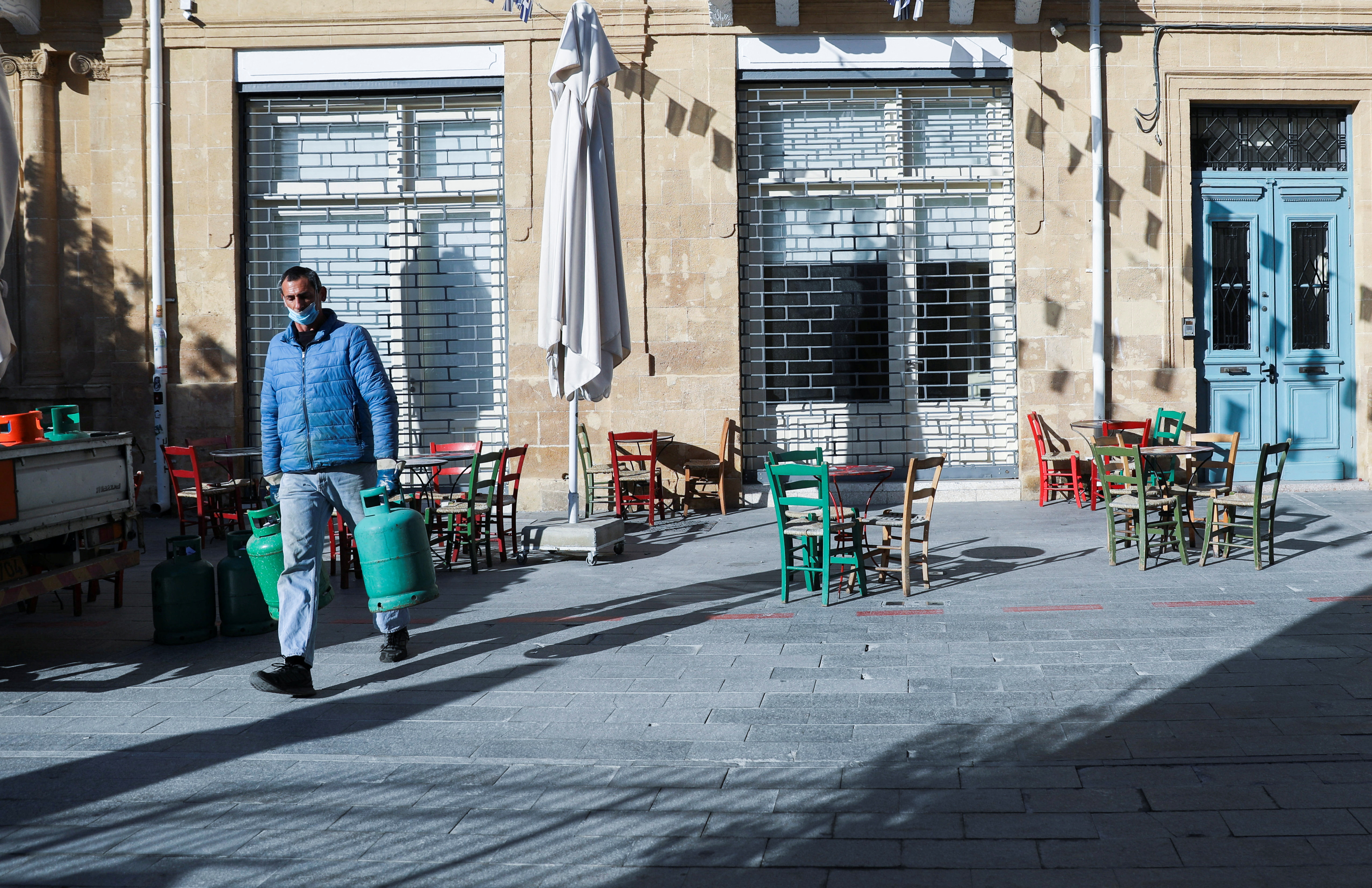 A man wearing a protective face mask carries gas bottles amid the coronavirus disease (COVID-19) outbreak in Nicosia, Cyprus