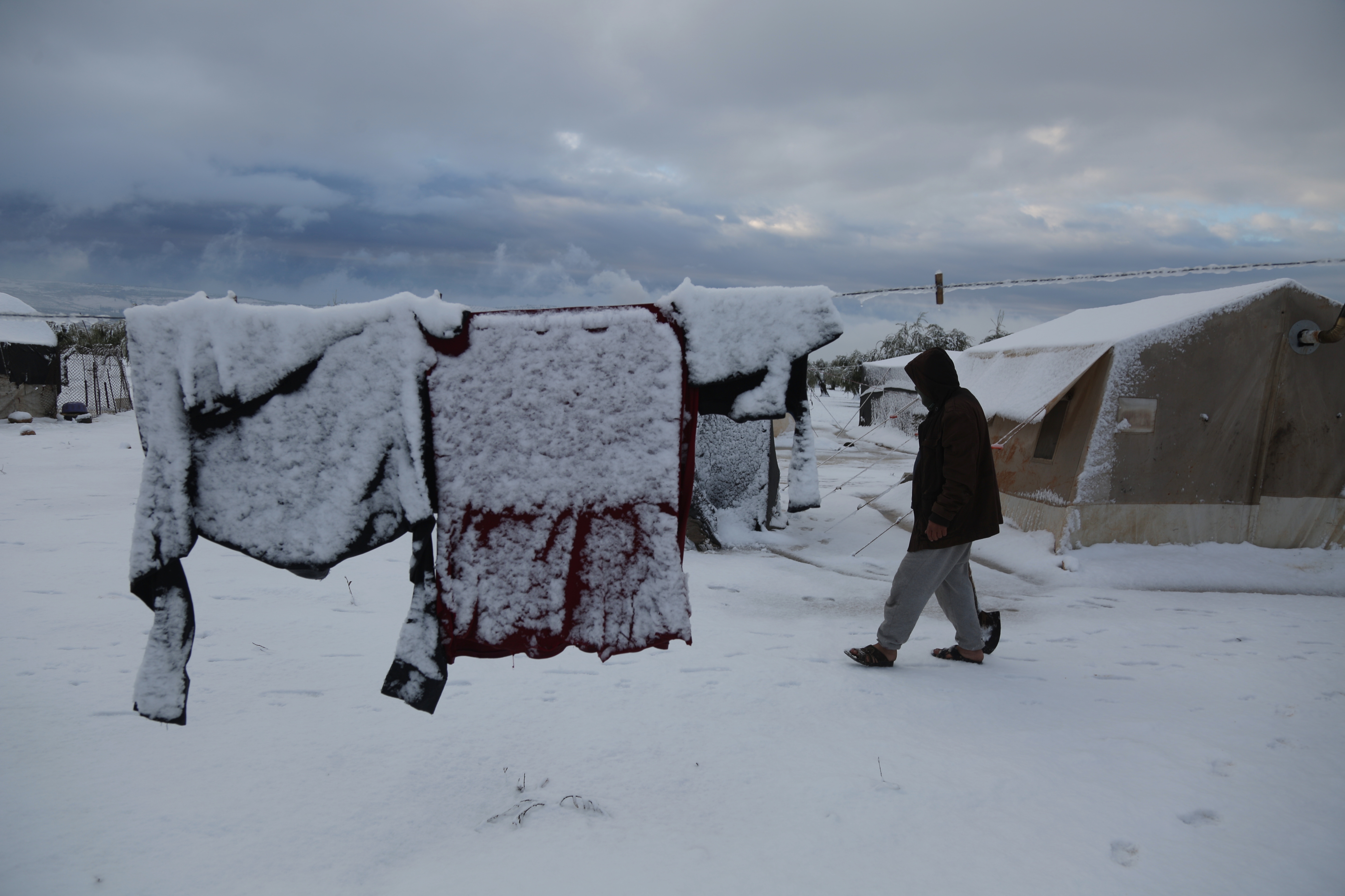 Snow covers clothes hanging on a line outside in Sheikh Bilal Camp in Afrin