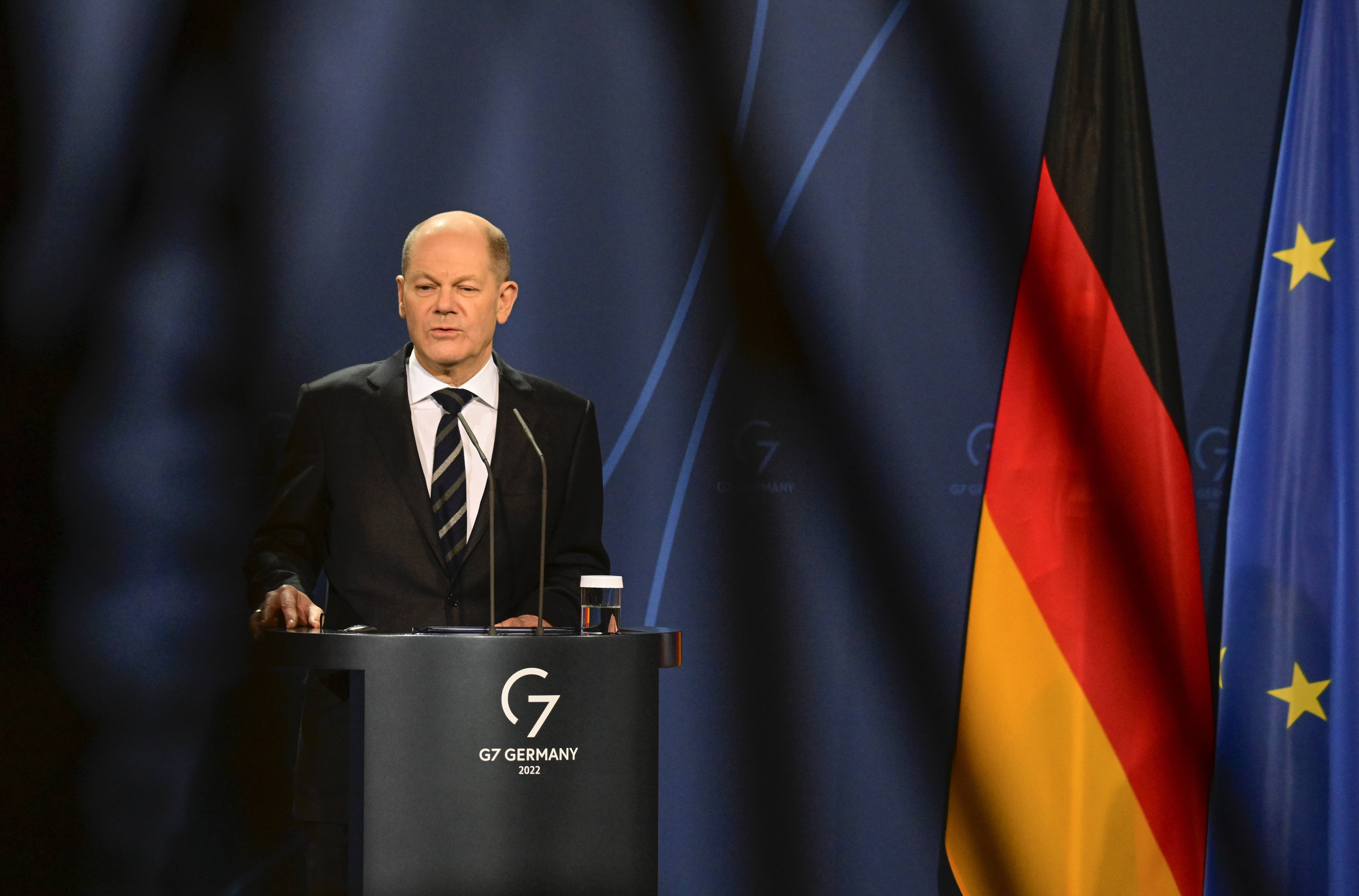 German Chancellor Olaf Scholz speaks during a media conference with the German flag in the background