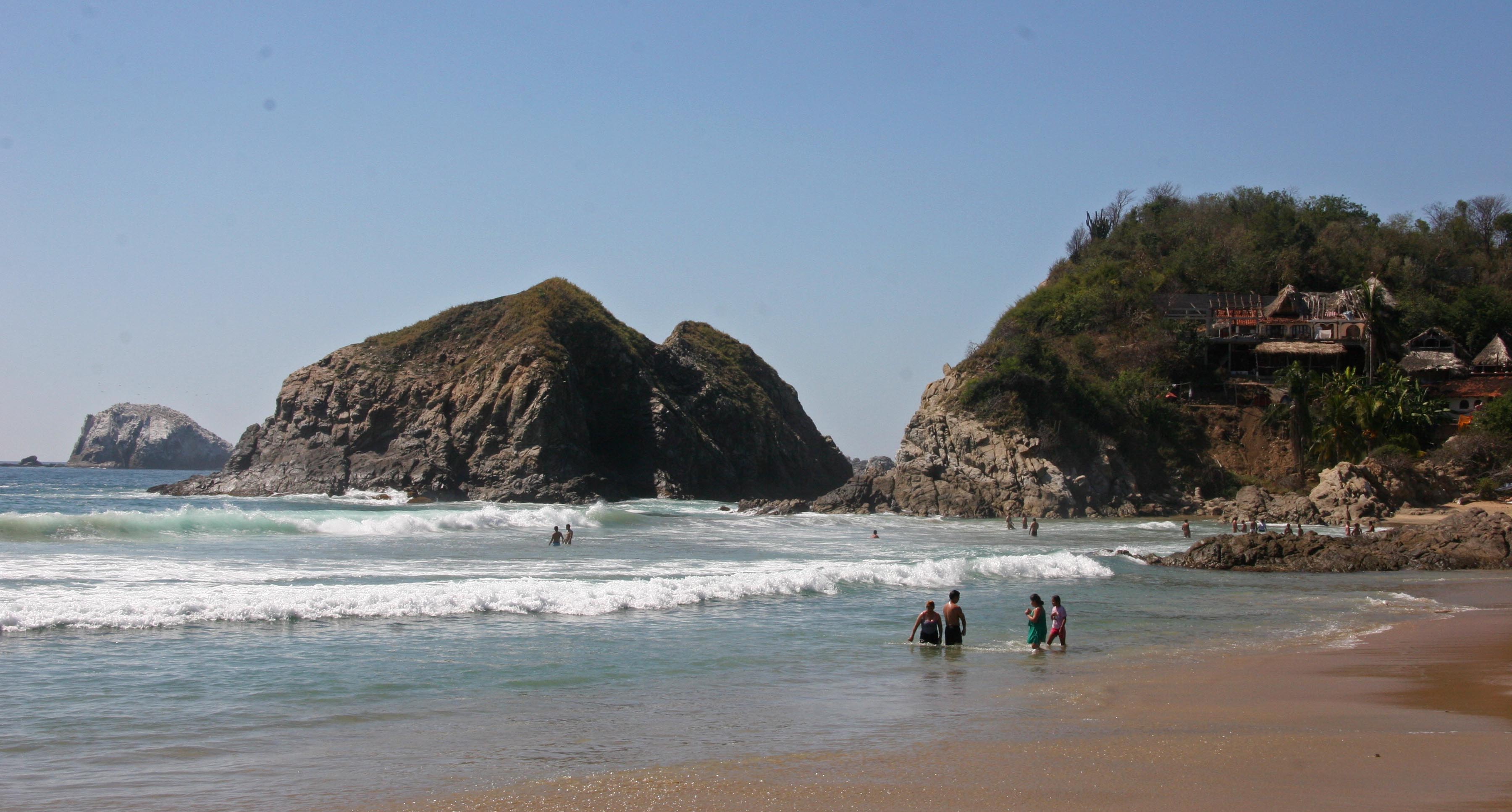 Visitors bathe in the surf along the beach in Zipolite, Mexico.